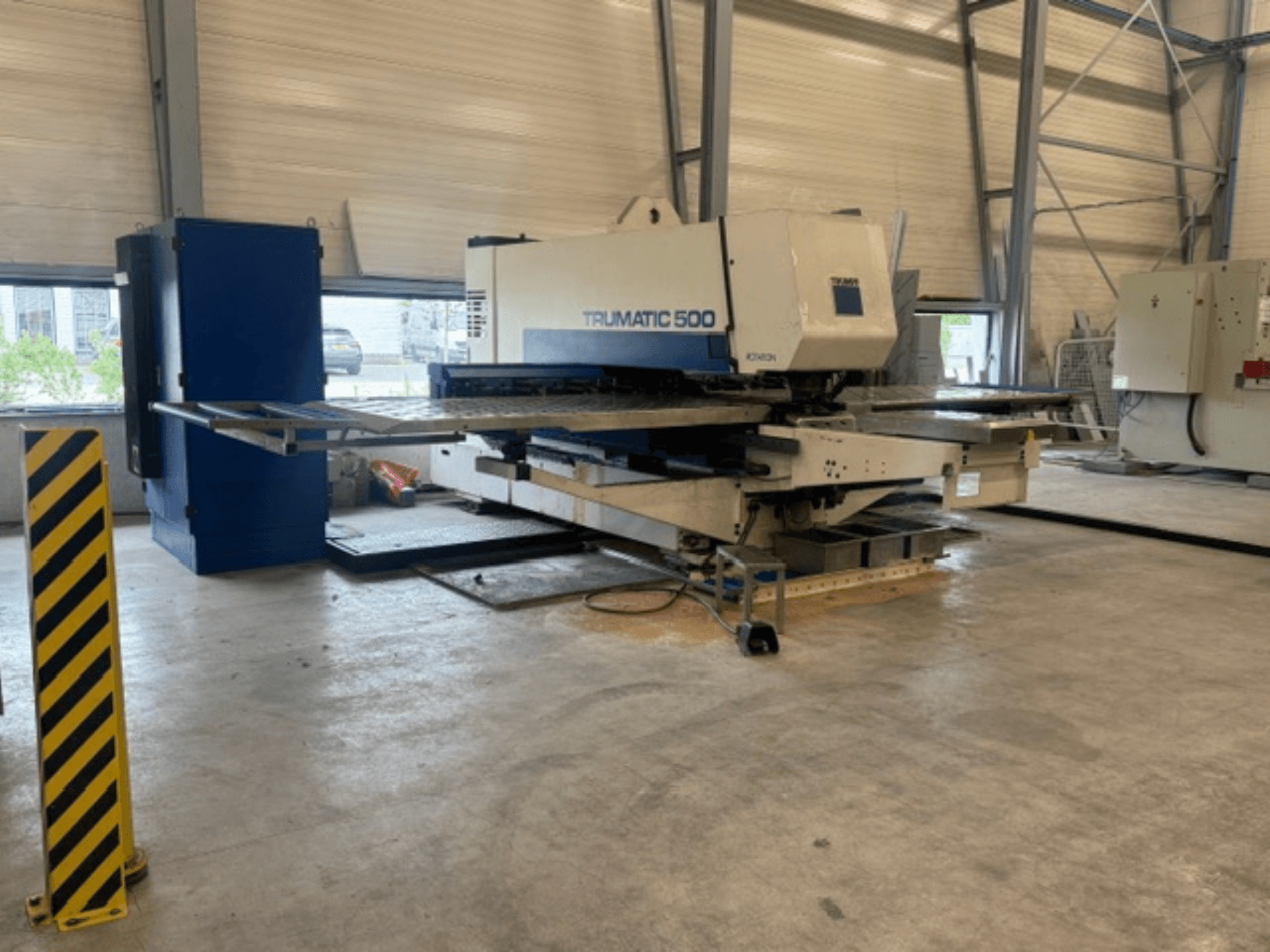 CNC-ponsmachine TRUMPF Trumatic 500 in een werkplaats, zijaanzicht met de machine en een veiligheidspaal met gele strepen.