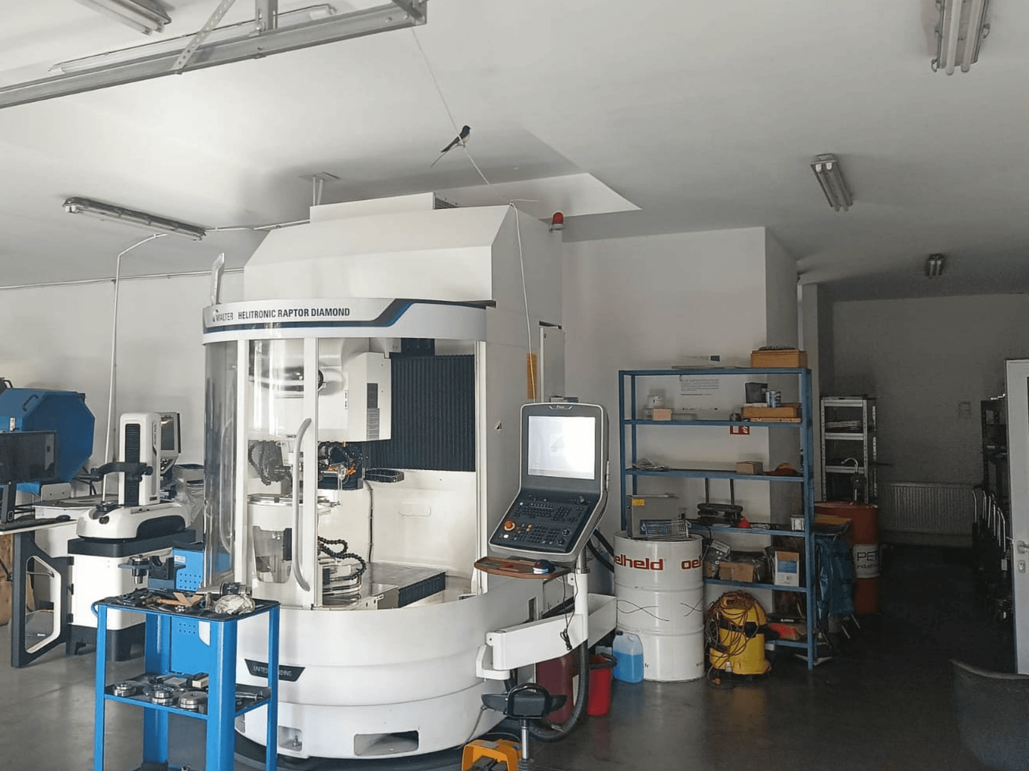 WALTER HELITRONIC RAPTOR DIAMOND cilindrische slijpmachine in een werkplaats, zijaanzicht met bedieningspaneel en gereedschap ernaast.