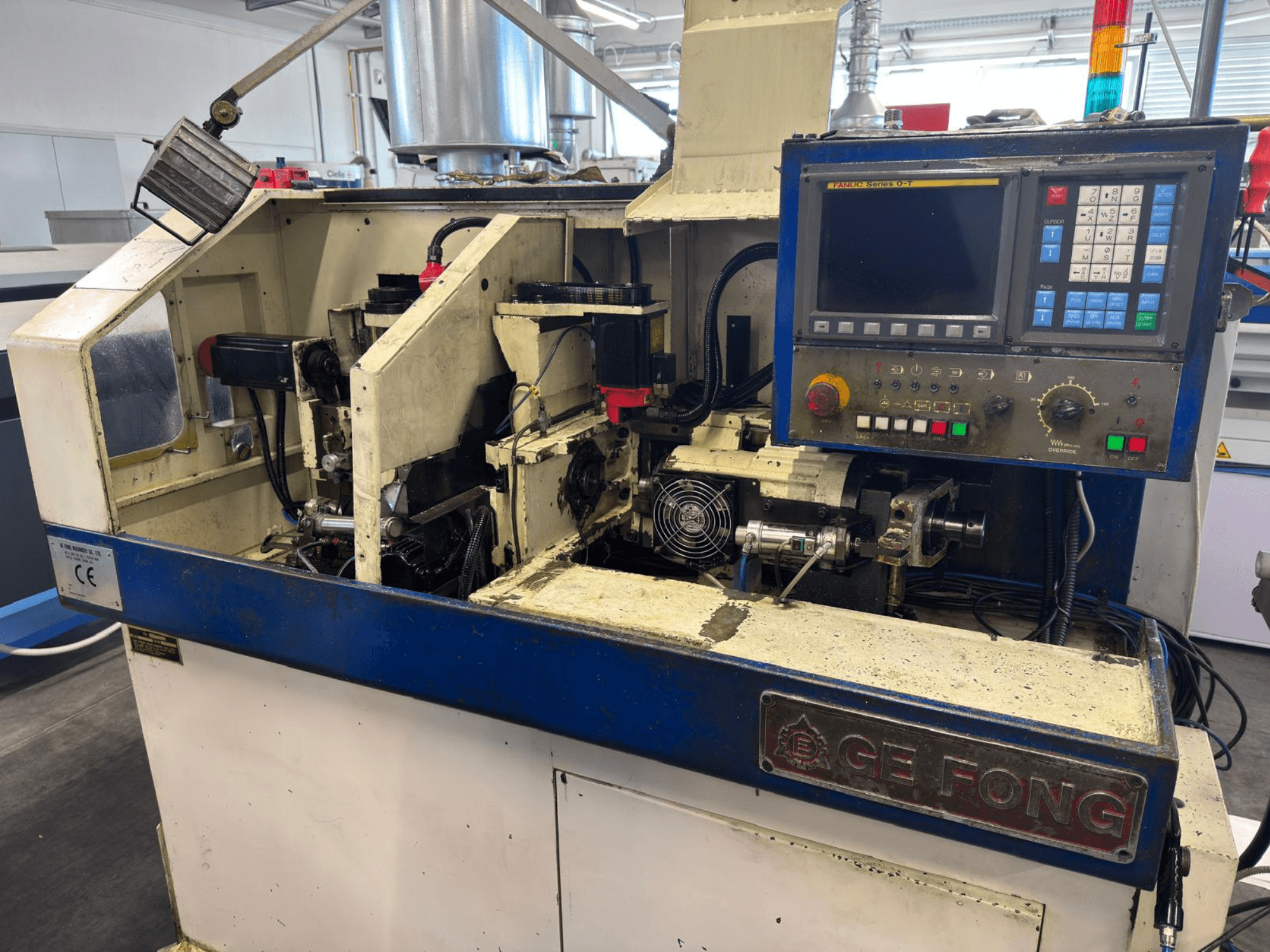 GE FONG industriële machine in vooraanzicht, met interne onderdelen, bedieningspaneel en operationele onderdelen.