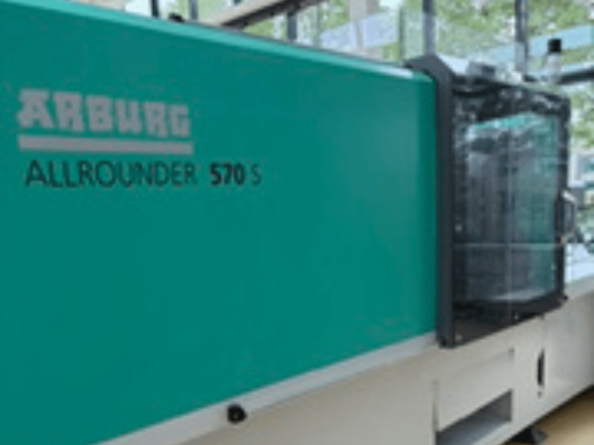 Vooraanzicht van de Arburg ALLROUNDER 570 S 1600-290, met een groenblauwe buitenkant en injectie-eenheid, waarop een deel van het machineontwerp te zien is.