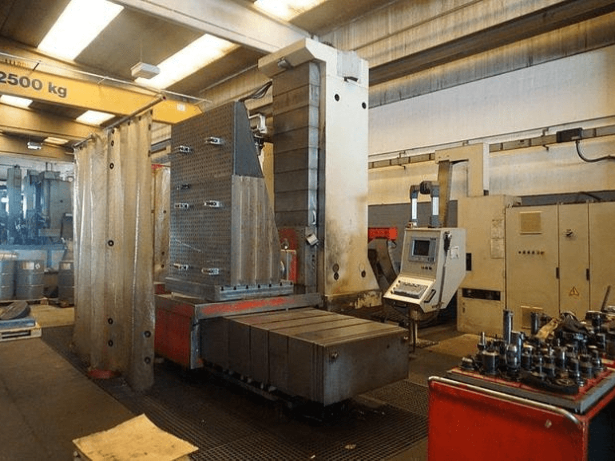 Industriële freesmachine met touchscreenbediening en grote werktafel, gezien vanaf de voorkant in een werkplaats.