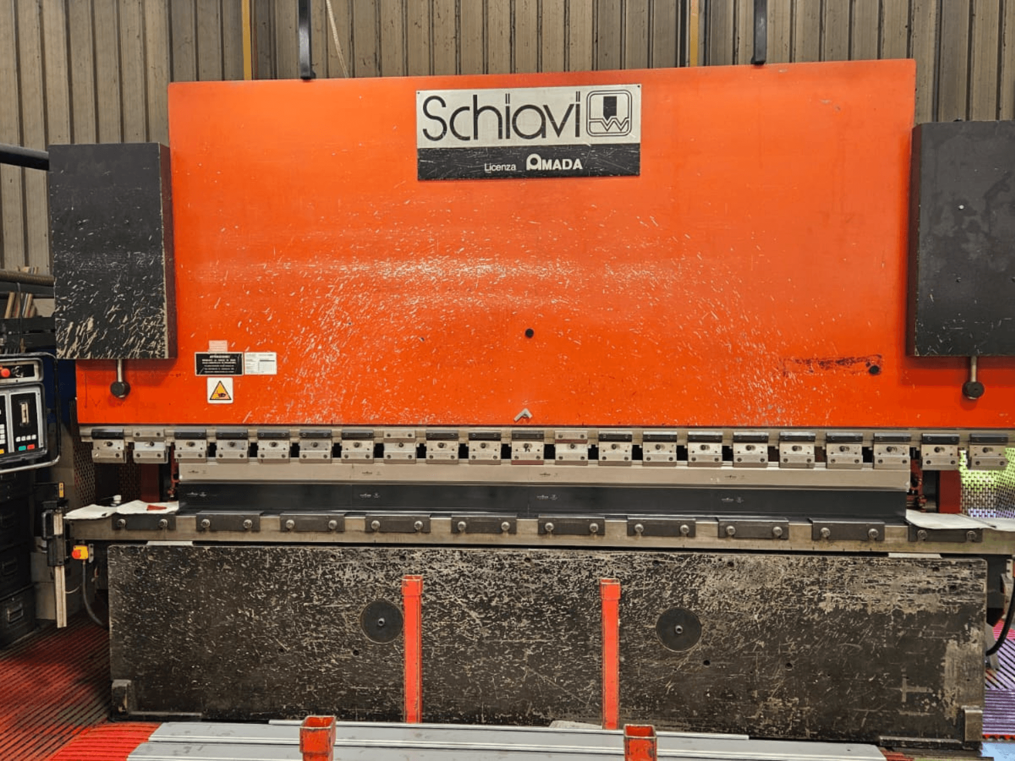 Schiavi Amada metaalbuigmachine, vooraanzicht, met oranje behuizing, bedieningspaneel links en meerdere buiggereedschappen zichtbaar.