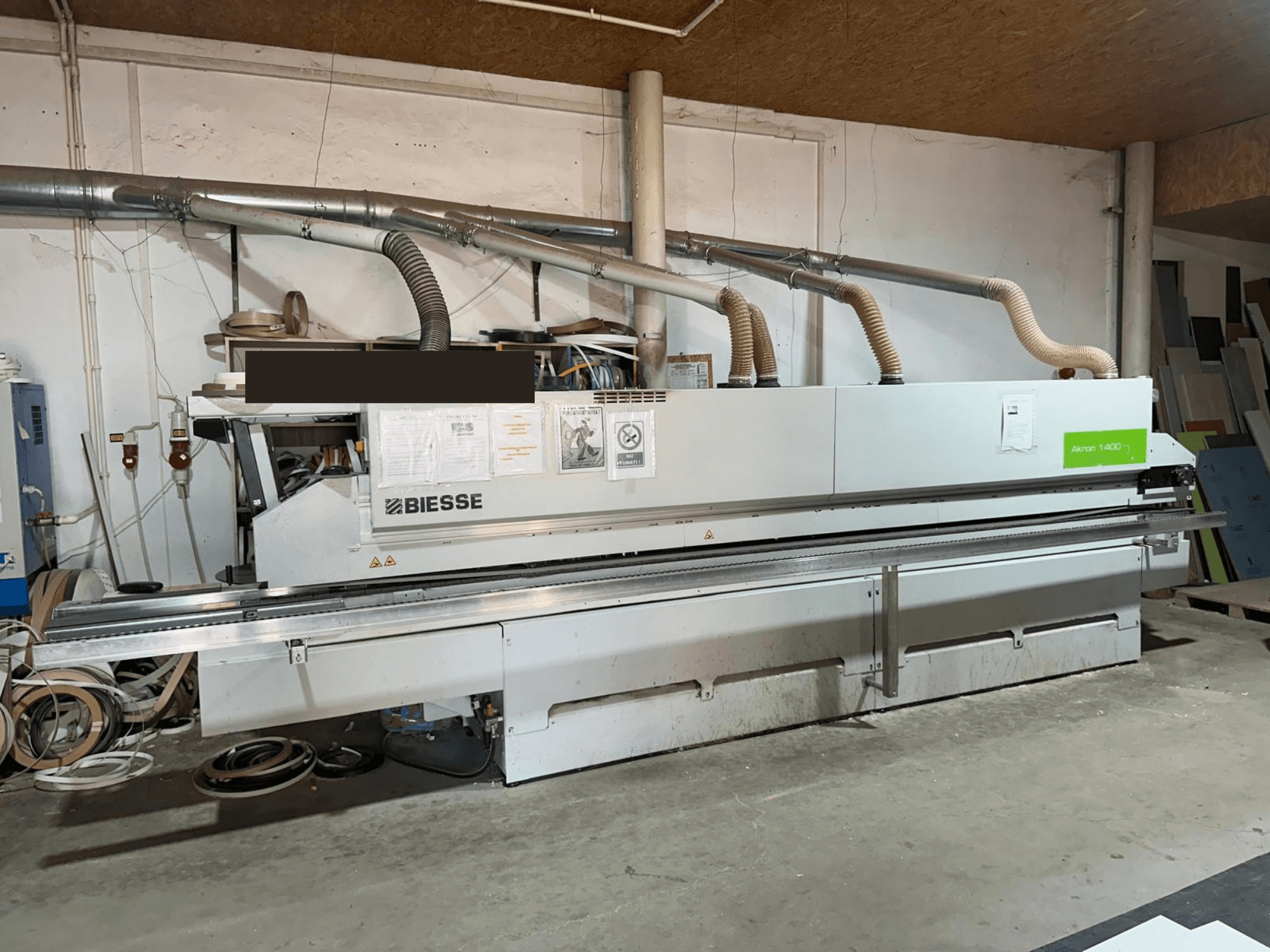 BIESSE AKRON 1440 A kantenlijmmachine, vooraanzicht, met zichtbaar bedieningspaneel en stofafzuigcomponenten in een werkplaatsomgeving.