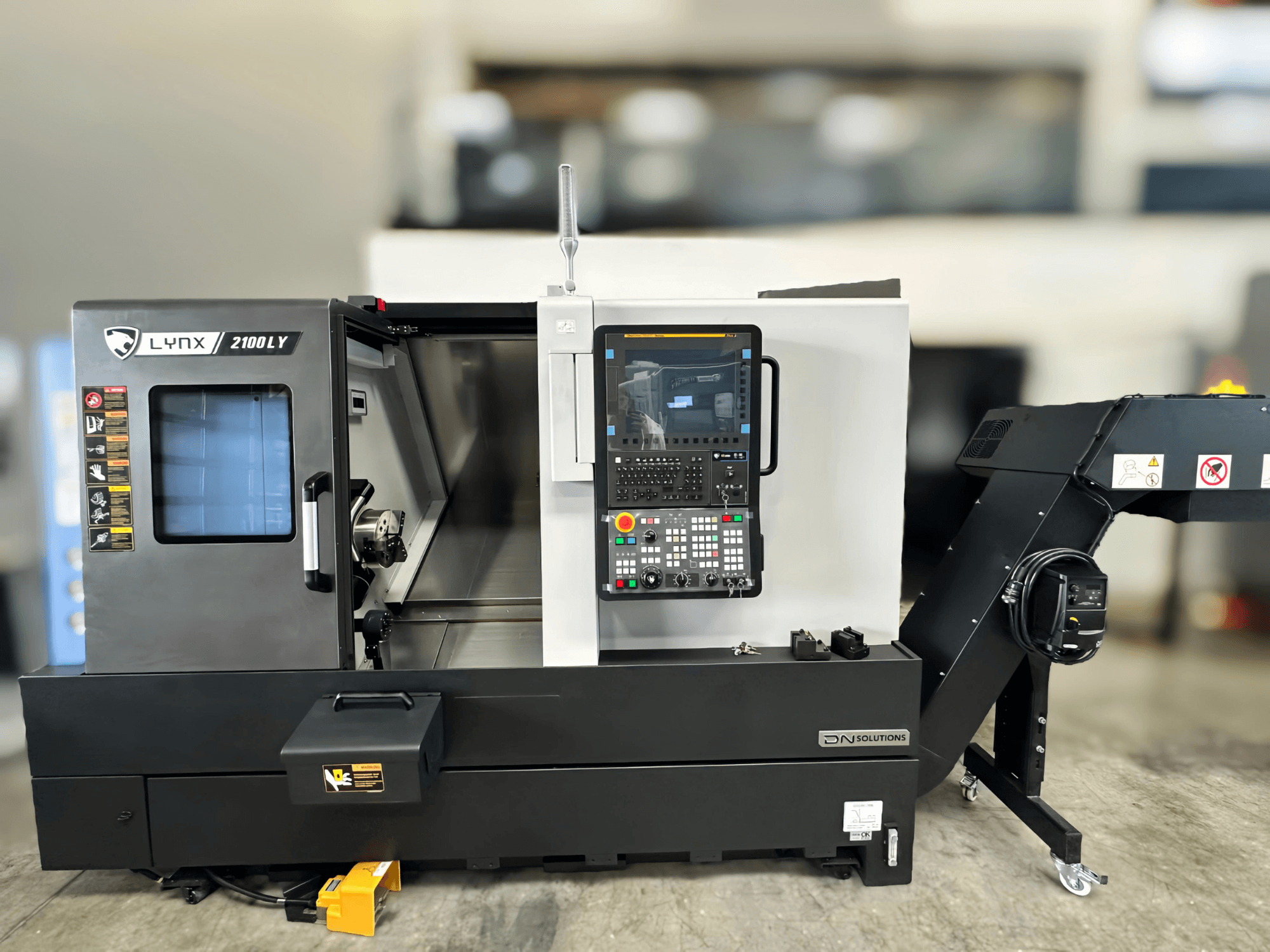 Horizontale draaimachine DN SOLUTIONS LYNX 2100LYB, vooraanzicht, met bedieningspaneel en open deur die het interieur onthult.