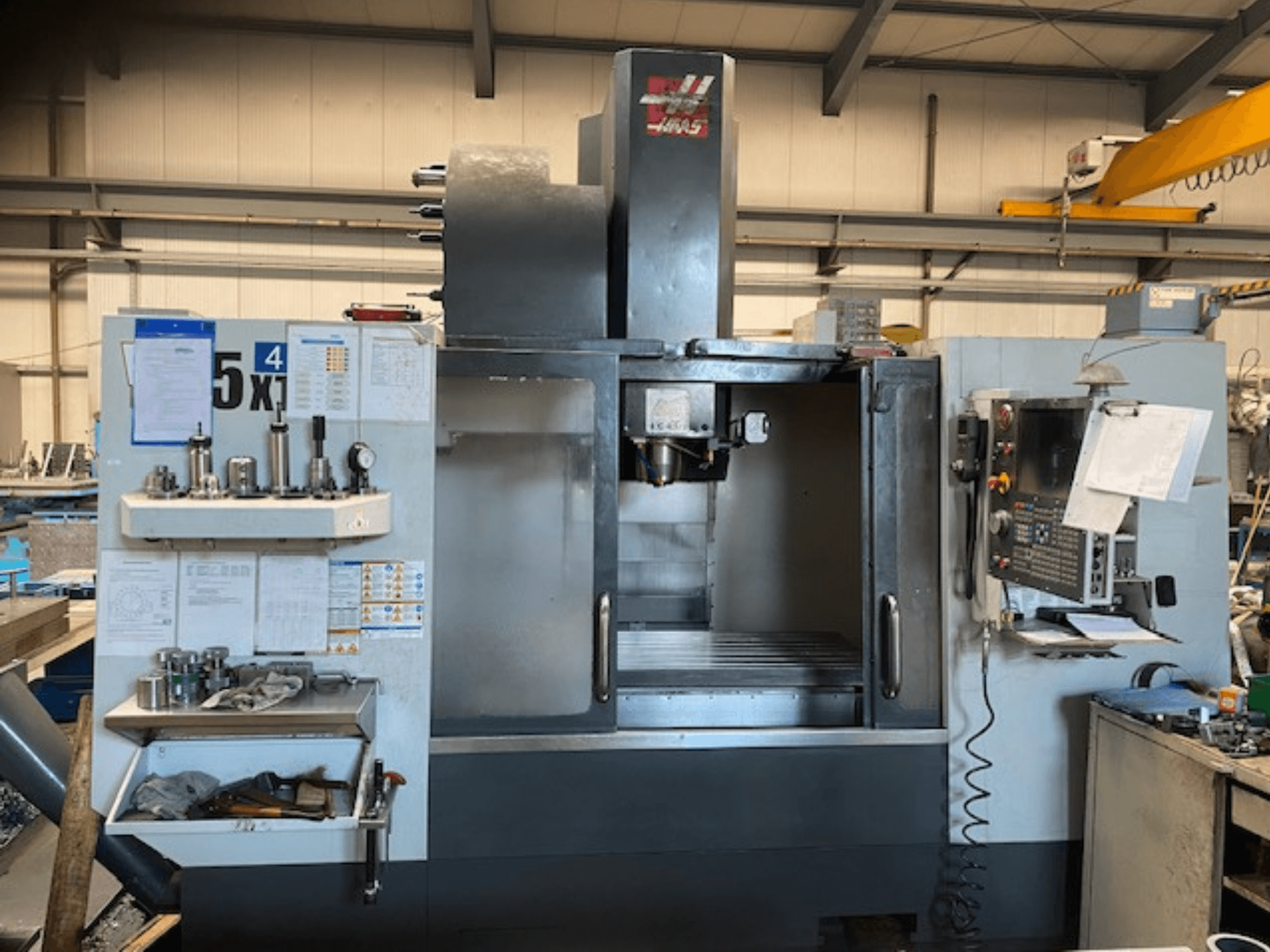 Haas VF-5 verticaal bewerkingscentrum, vooraanzicht, met het bedieningspaneel, de gereedschapopslag en het spindelgebied.