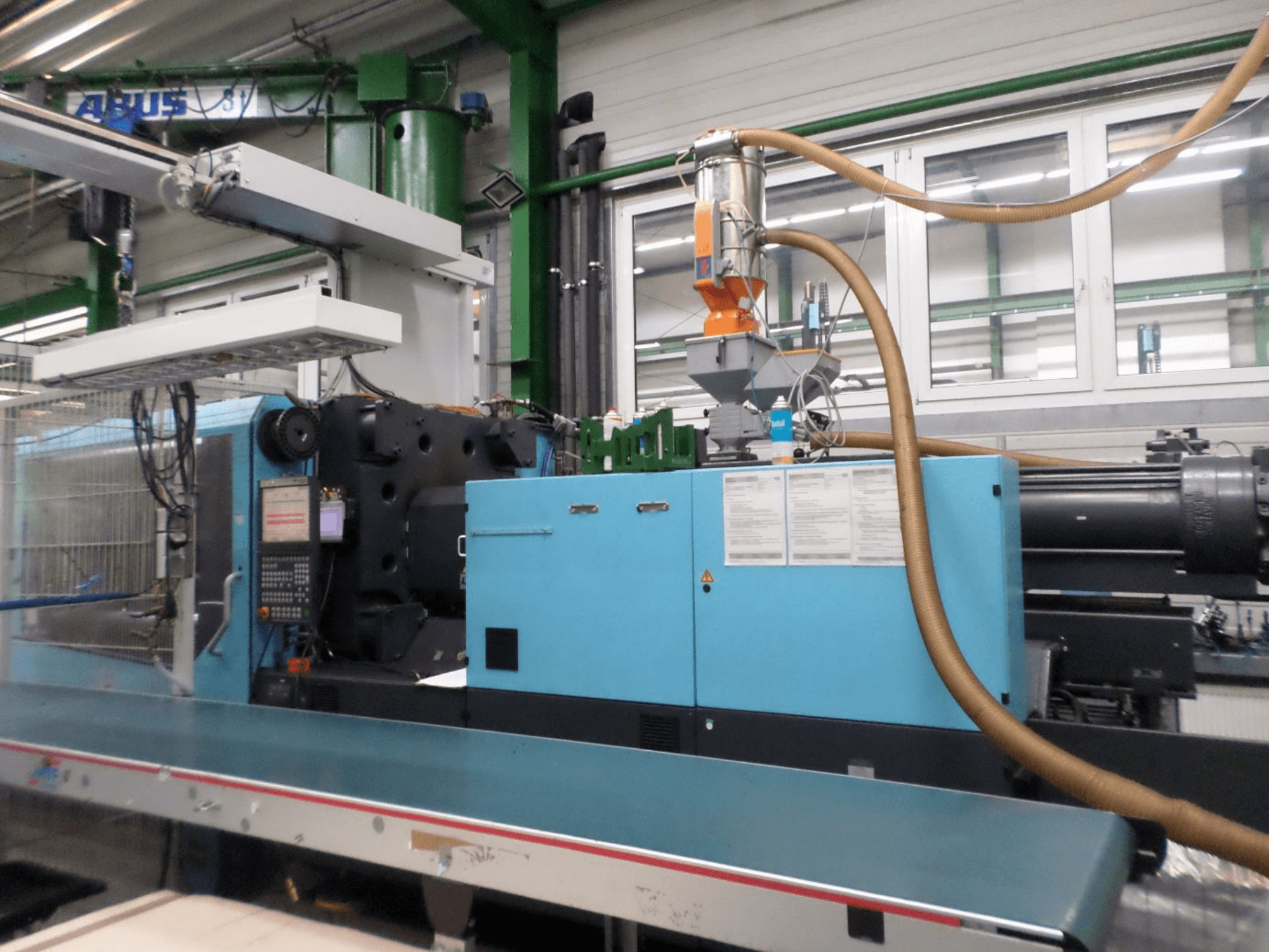 Vooraanzicht van een DEMAG D 420 hydraulische spuitgietmachine, met daarop het bedieningspaneel, de trechter en de hydraulische onderdelen.