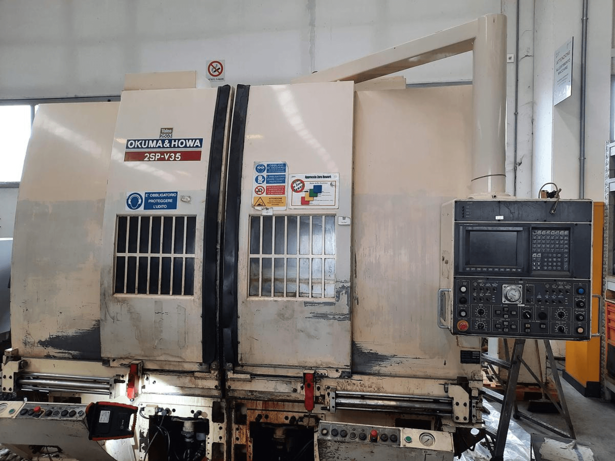 OKUMA & HOWA 2SP-V35 CNC machine gezien vanaf de voorkant, met bedieningspaneel met diverse knoppen en veiligheidslabels.