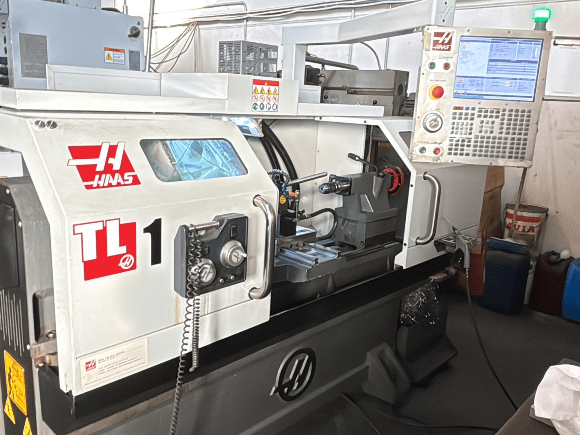 Haas TL-1 CNC draaibank, vooraanzicht, voorzien van bedieningspaneel met display, gereedschaphouder en veiligheidslabels.