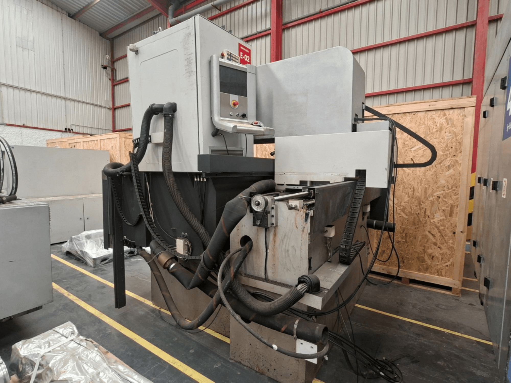 ONA NX7 zink-EDM-machine, zijaanzicht met bedieningspaneel, slangen en bewerkingsgebied in een werkplaatsomgeving.