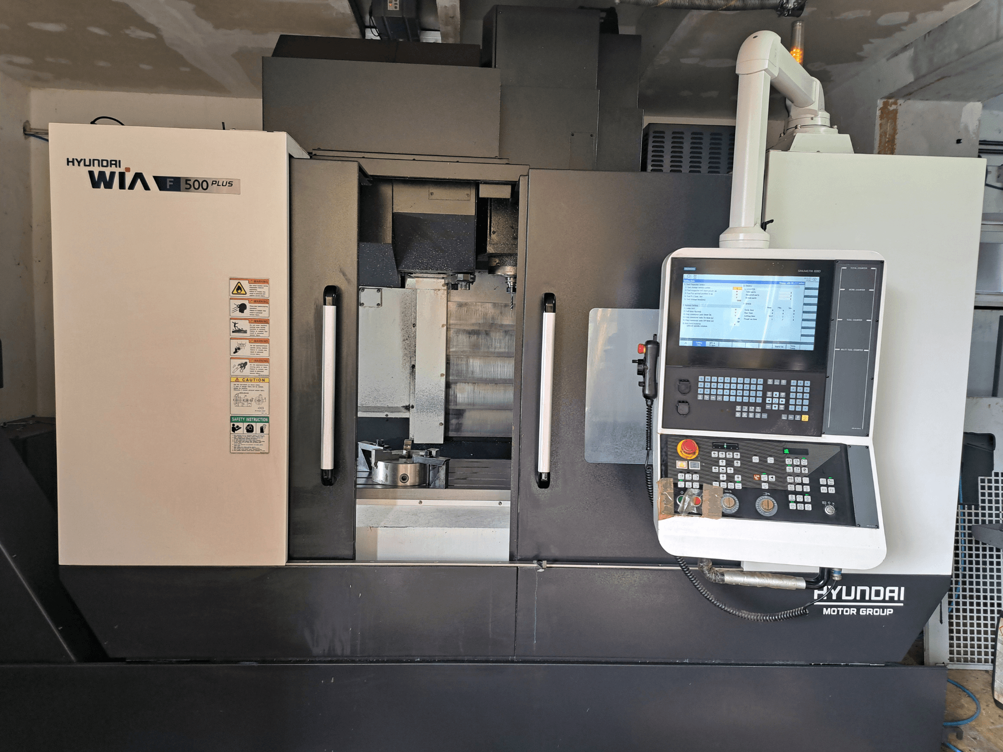 Hyundai WIA F500 Plus CNC machine in vooraanzicht, met digitaal bedieningspaneel en veiligheidslabels.