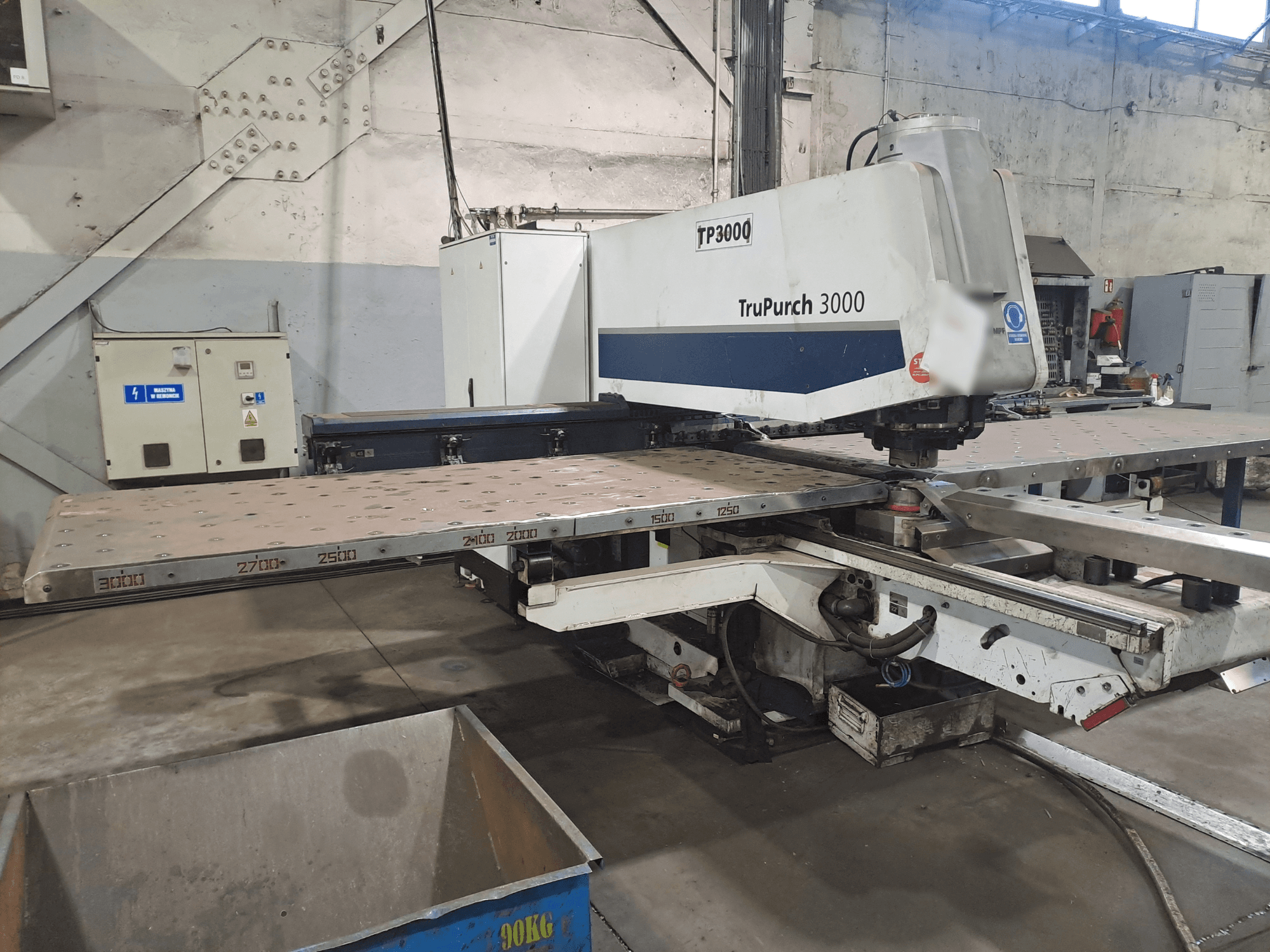 TruPunch 3000 CNC machine getoond vanaf de voorkant, met een grote metalen plaat en maatmarkeringen, in een industriële omgeving.