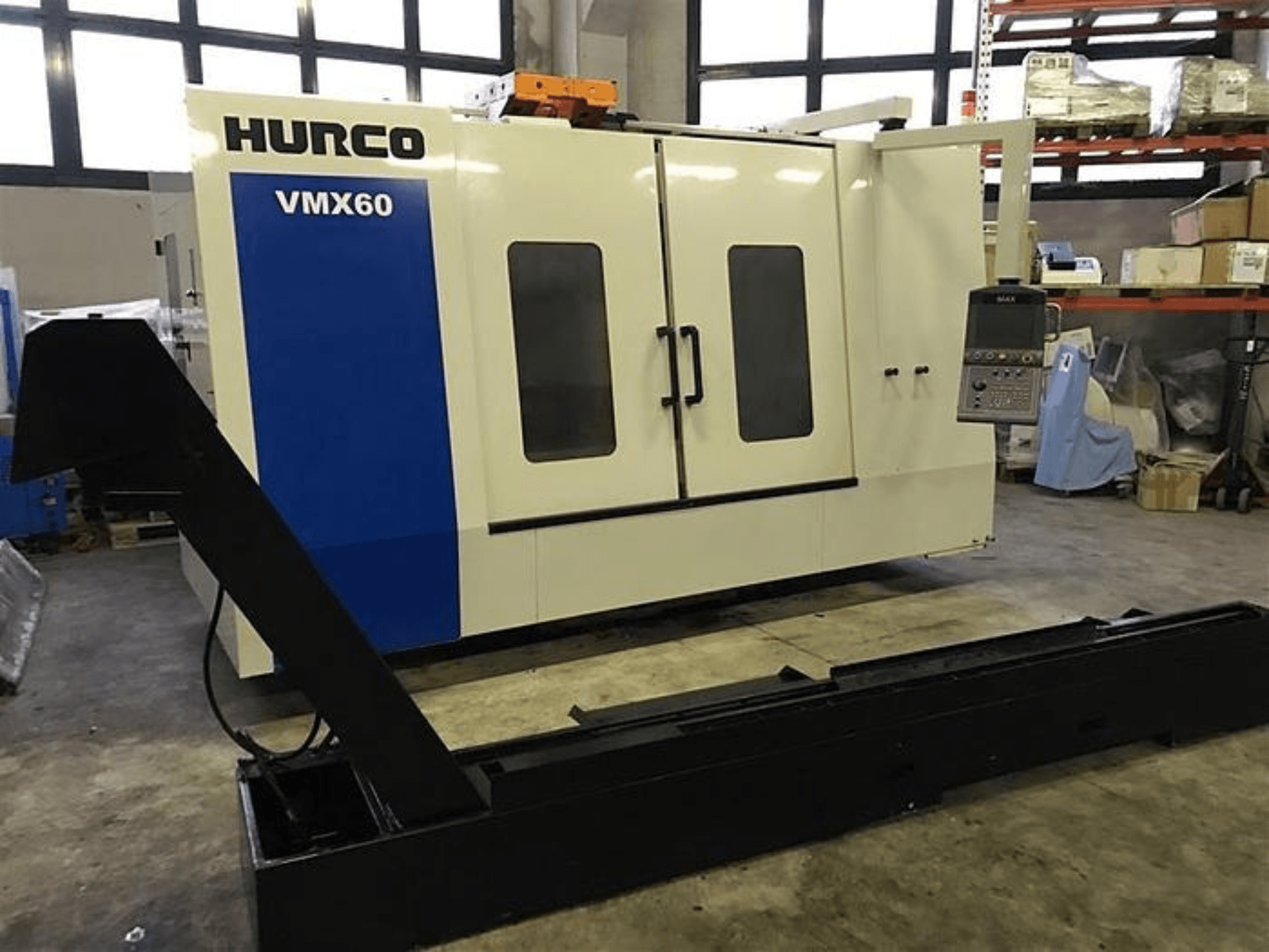 HURCO VMX60 CNC machine in een werkplaats, vooraanzicht, met een bedieningspaneel en bevestigde zwarte steunrail.