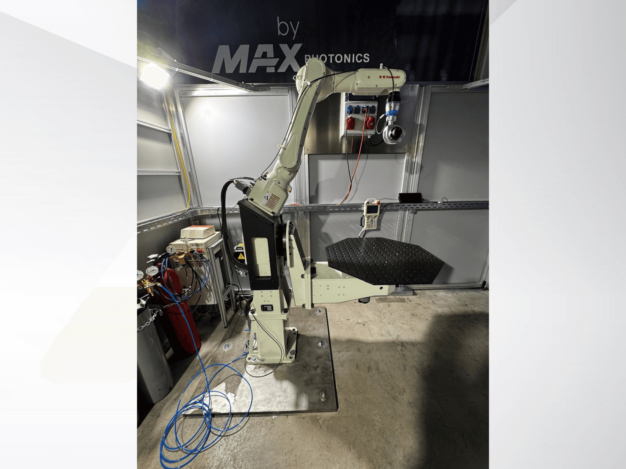 Max Photonics robotarmapparaat, vooraanzicht, met een zwart geperforeerd platform en bedieningspaneel met meters en kabels.