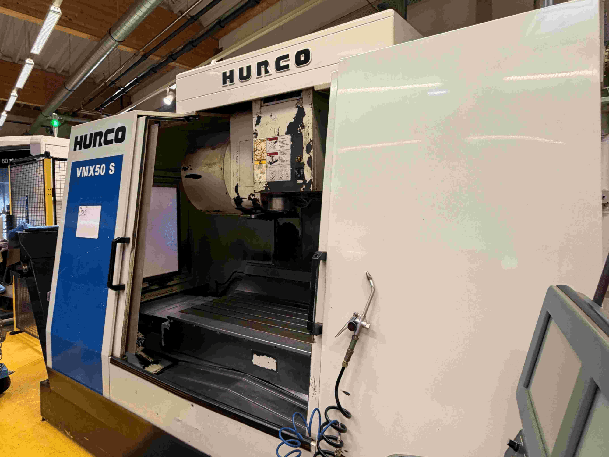 Hurco VMX50 S verticaal bewerkingscentrum, zijaanzicht, met de open deur en het bedieningspaneel.