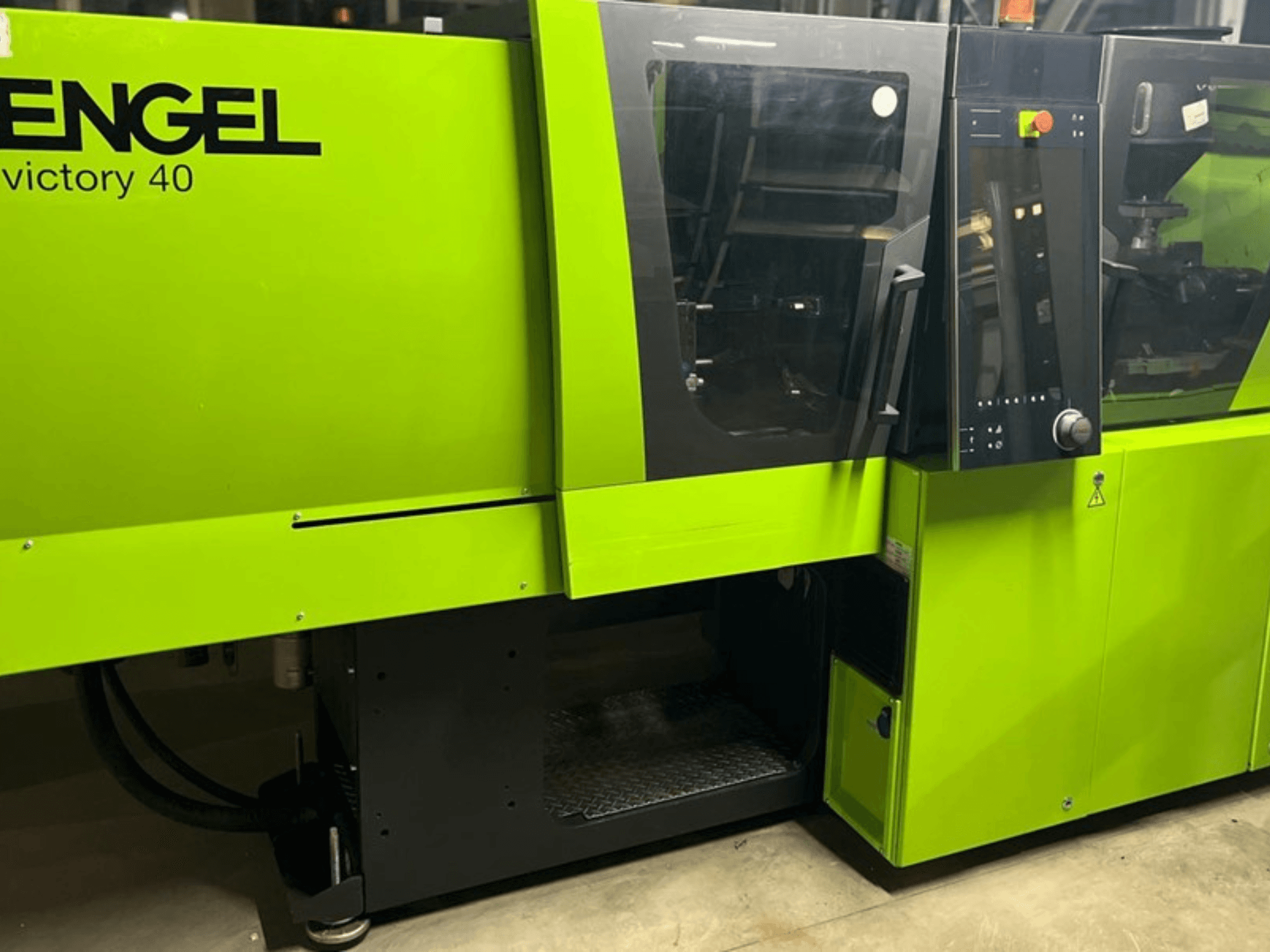 ENGEL Victory 40 spuitgietmachine in helder groen, vooraanzicht met bedieningspaneel en toegangsdeur met waarschuwingslabel.