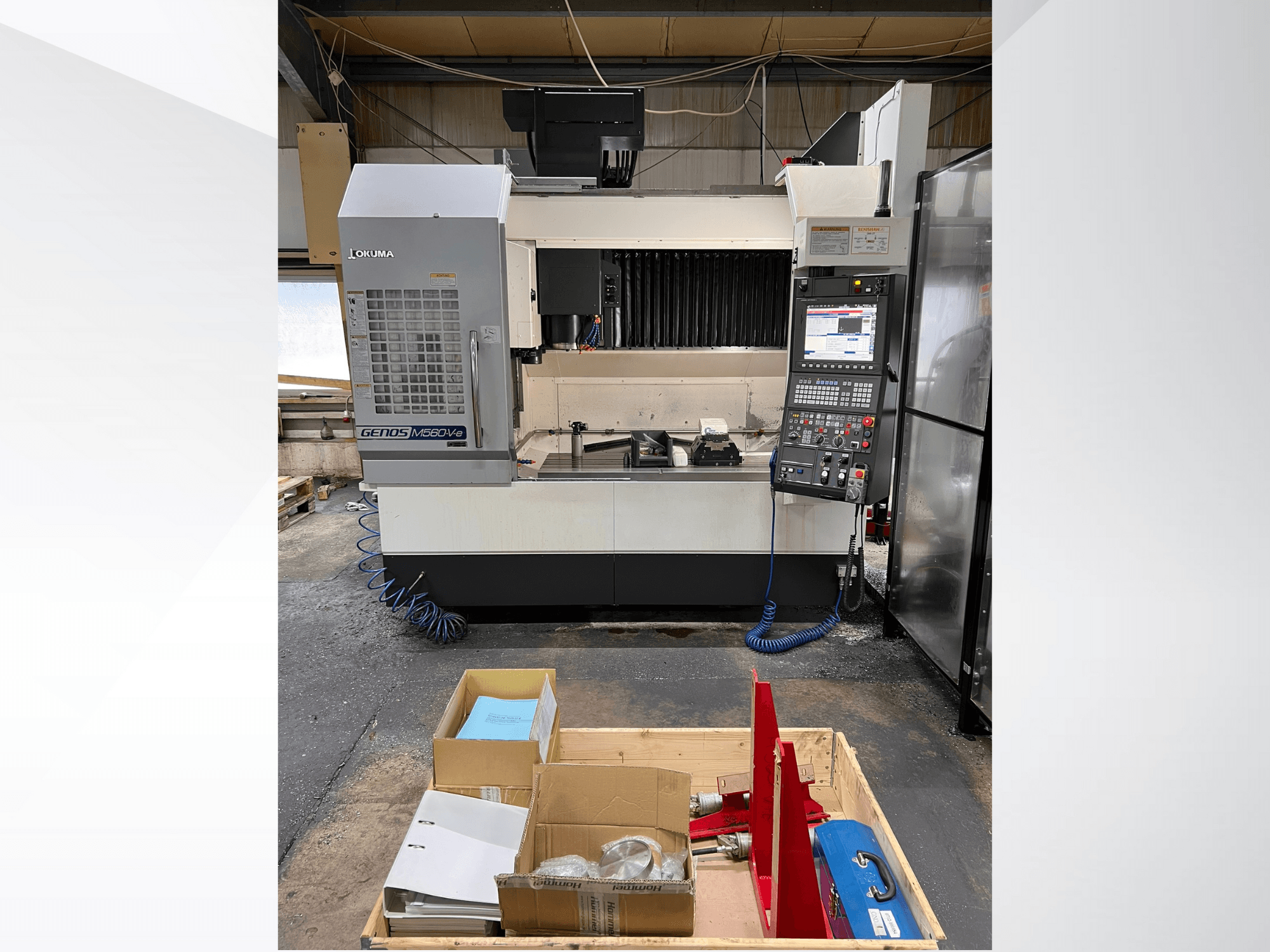 Okuma GENOS M460V-5 verticaal bewerkingscentrum, vooraanzicht, met bedieningspaneel zichtbaar en gereedschappen op de werktafel.