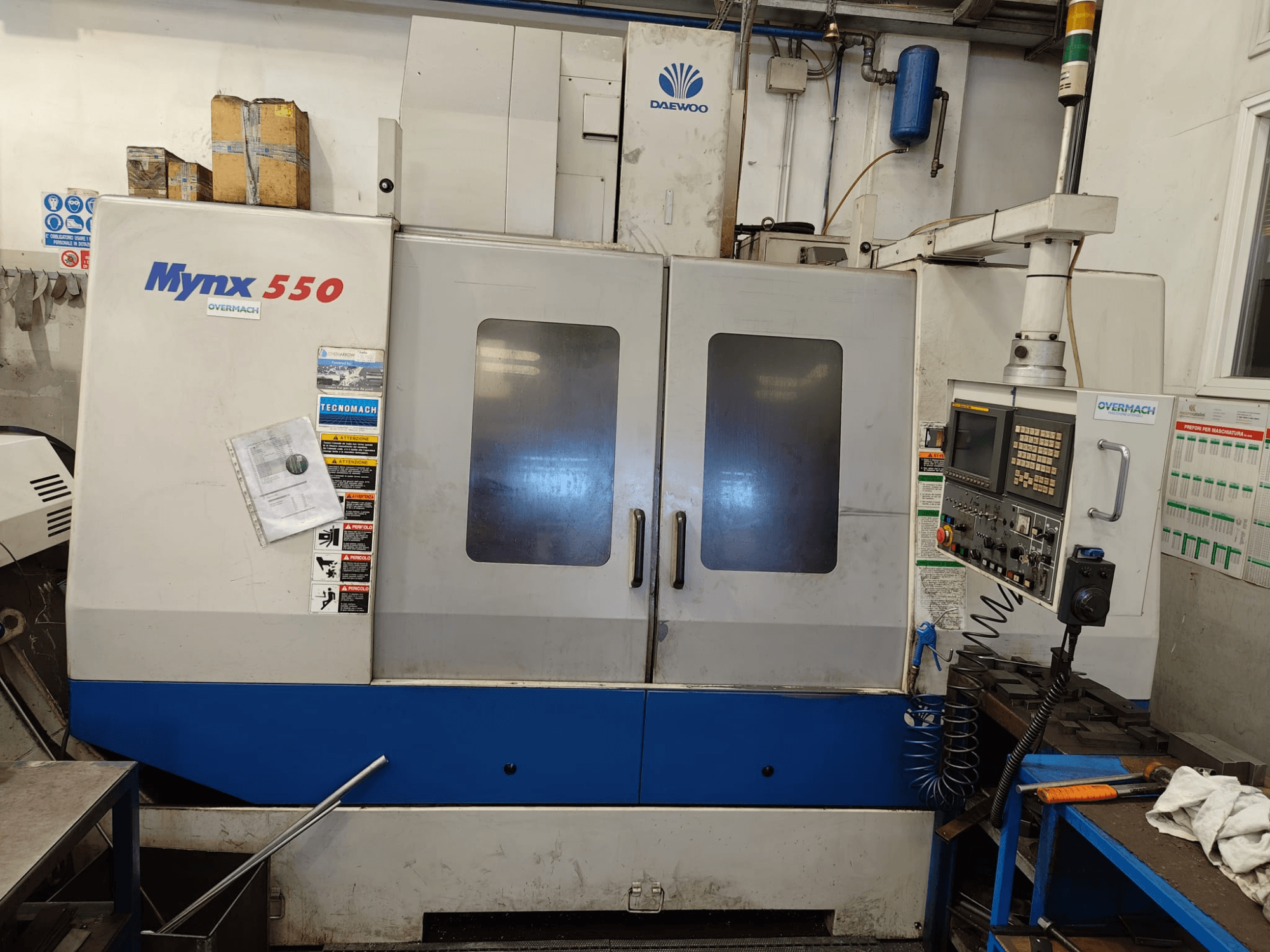 Verticaal bewerkingscentrum DAEWOO MYNX 550, vooraanzicht, met bedieningspaneel, twee grote deuren en veiligheidsstickers.
