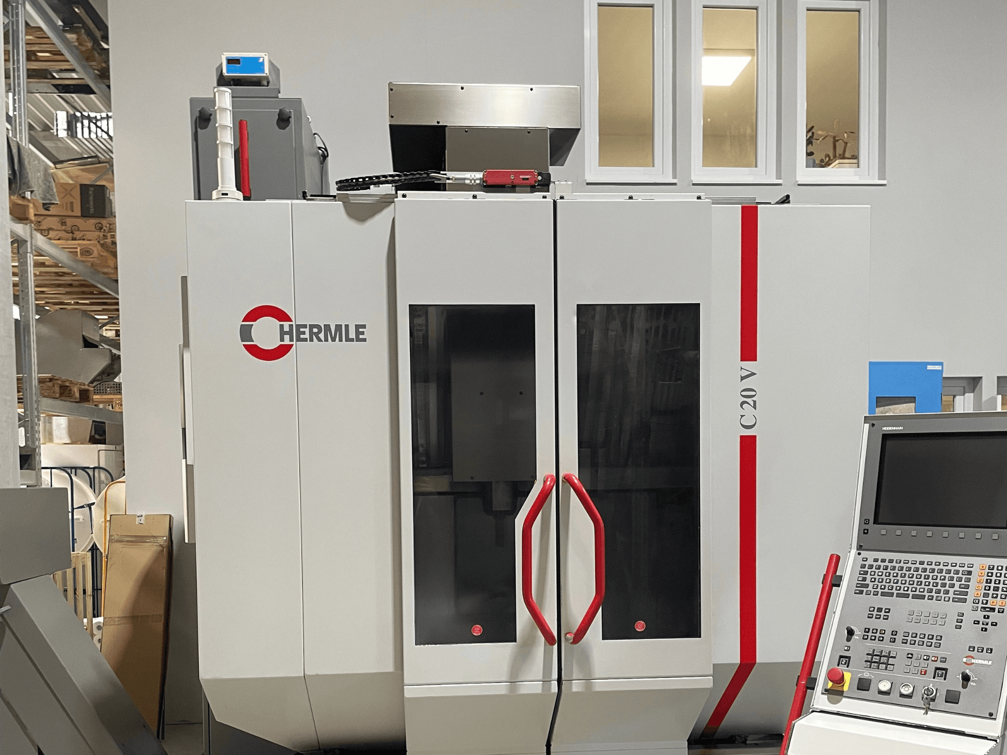 Chermle C20 V CNC machine, vooraanzicht, met bedieningspaneel en rode handgrepen; industrieel ontwerp met grote glazen deuren.