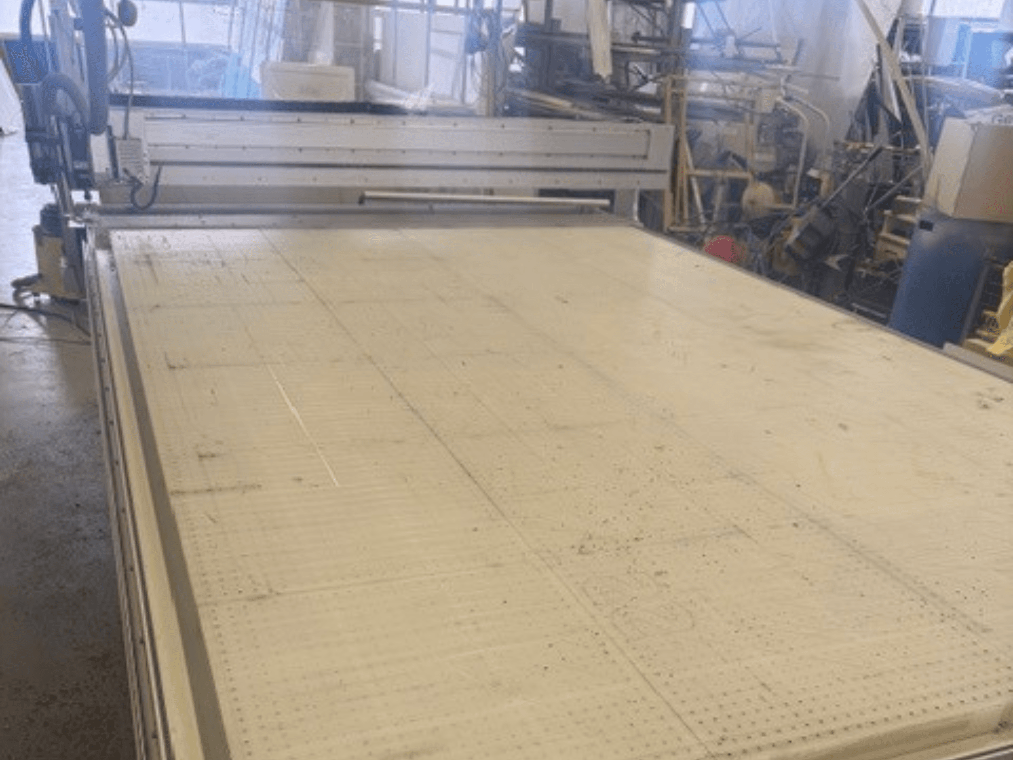 Grote snijmachine met een vlak oppervlak, met frame en geleiderail; gezien vanuit een hoek in een werkplaats.