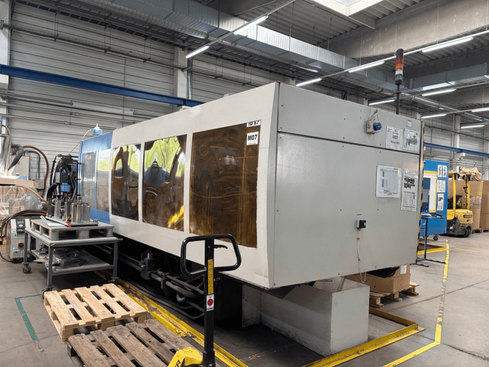 HAITIAN 7000/5000 hydraulische spuitgietmachine in een fabriek, zijaanzicht met zichtbare bedieningspanelen en veiligheidslampjes.