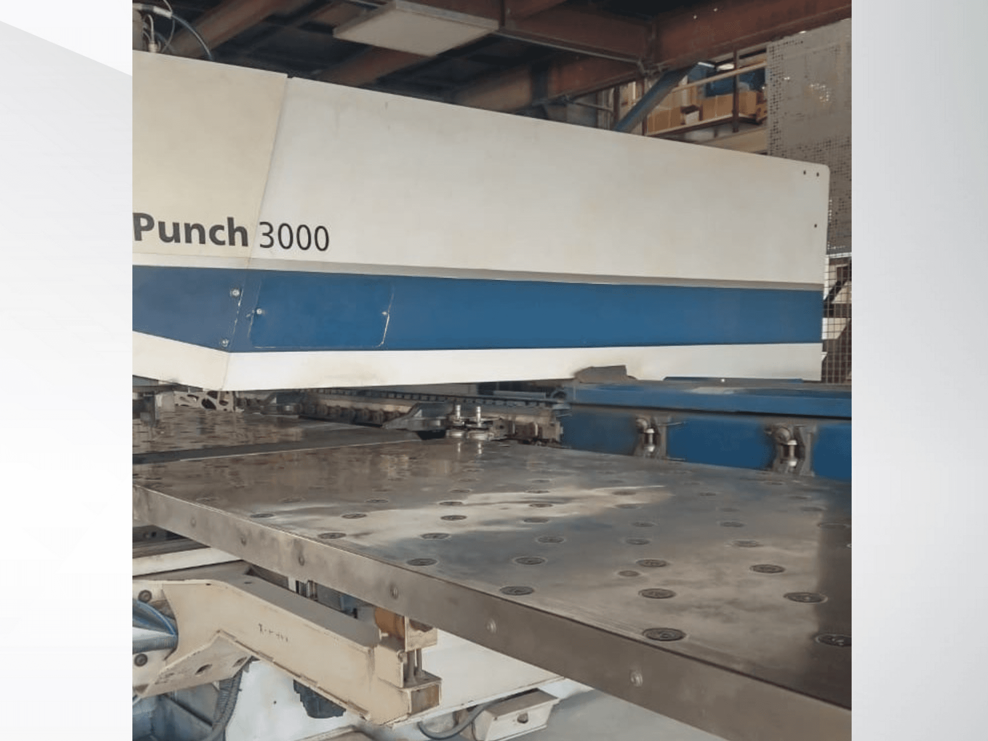 Ponsmachine 3000 in een werkplaats, vooraanzicht, met een groot, plat metalen oppervlak met meerdere ponsgaten.