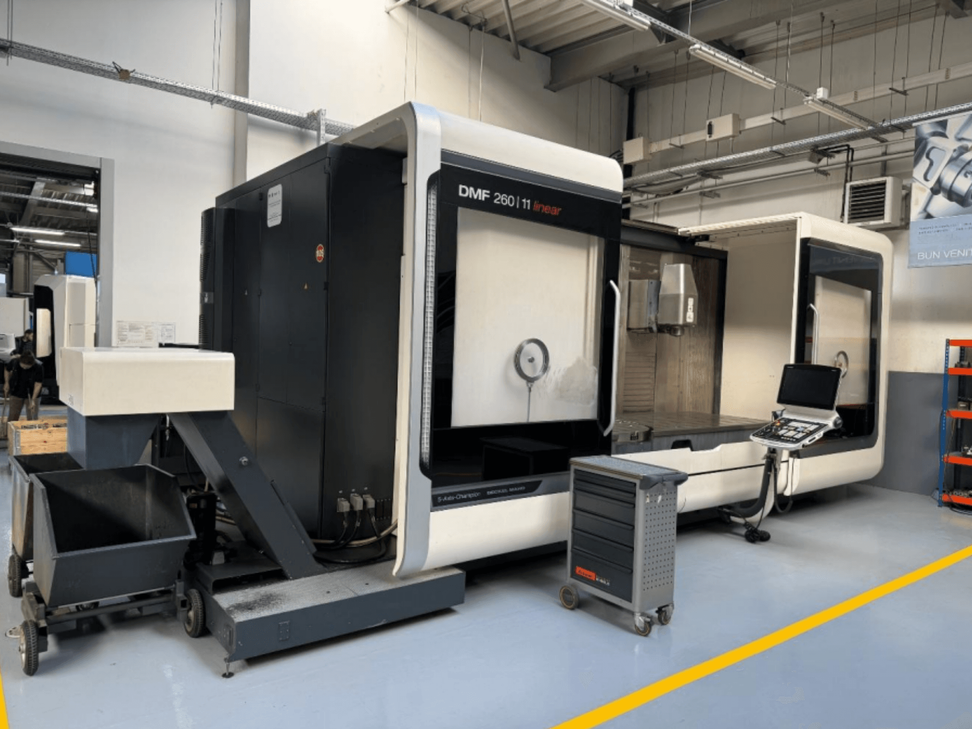 DMG MORI DMF 260 lineaire freesmachine van voren gezien, met een bedieningspaneel en een mobiele gereedschapswagen in de buurt.