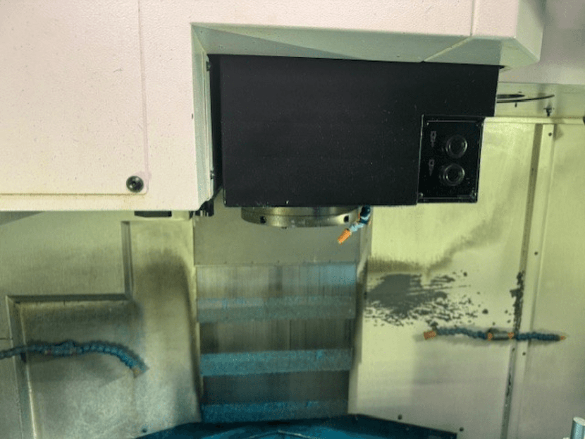 Close-up van het bedieningspaneel en de gereedschapshouder van een CNC freesmachine, met merkdetails, knoppen en werkoppervlak.