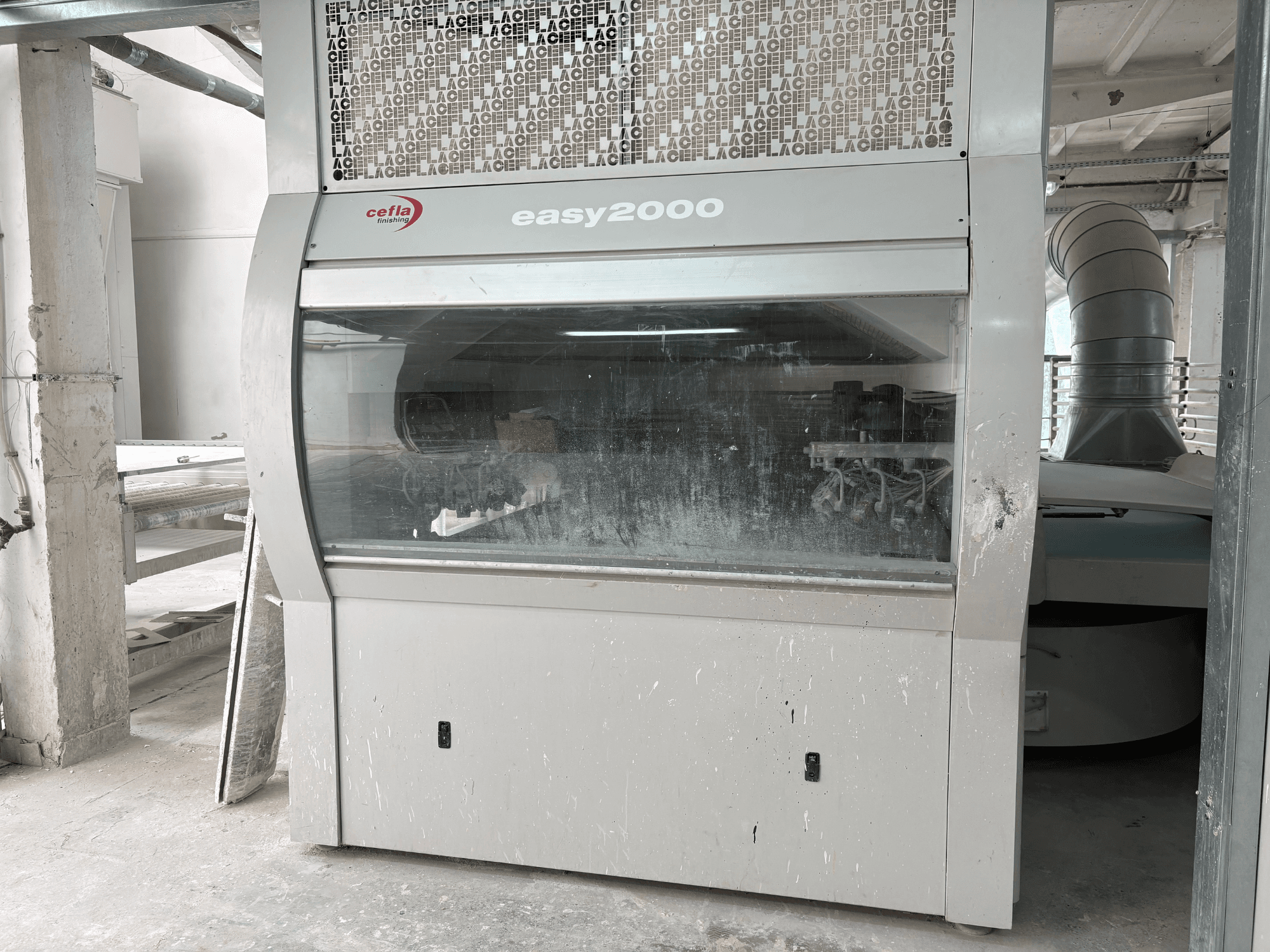 De Cefla EASY 2000 D-machine in vooraanzicht, met een groot doorzichtig paneel, een stoffig oppervlak en zichtbare interne onderdelen.