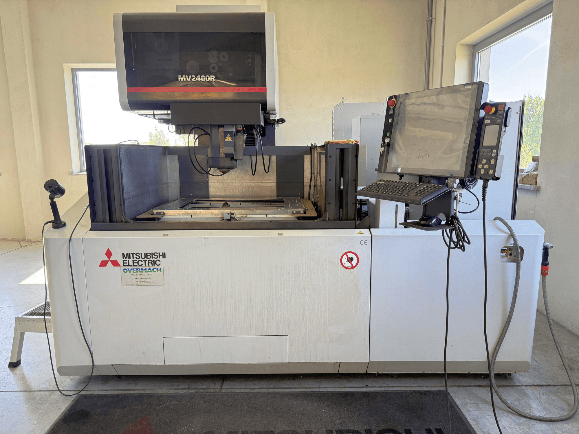 Mitsubishi MV2400R draadvonkmachine in vooraanzicht, met bedieningspaneel, werkruimte en veiligheidsborden.