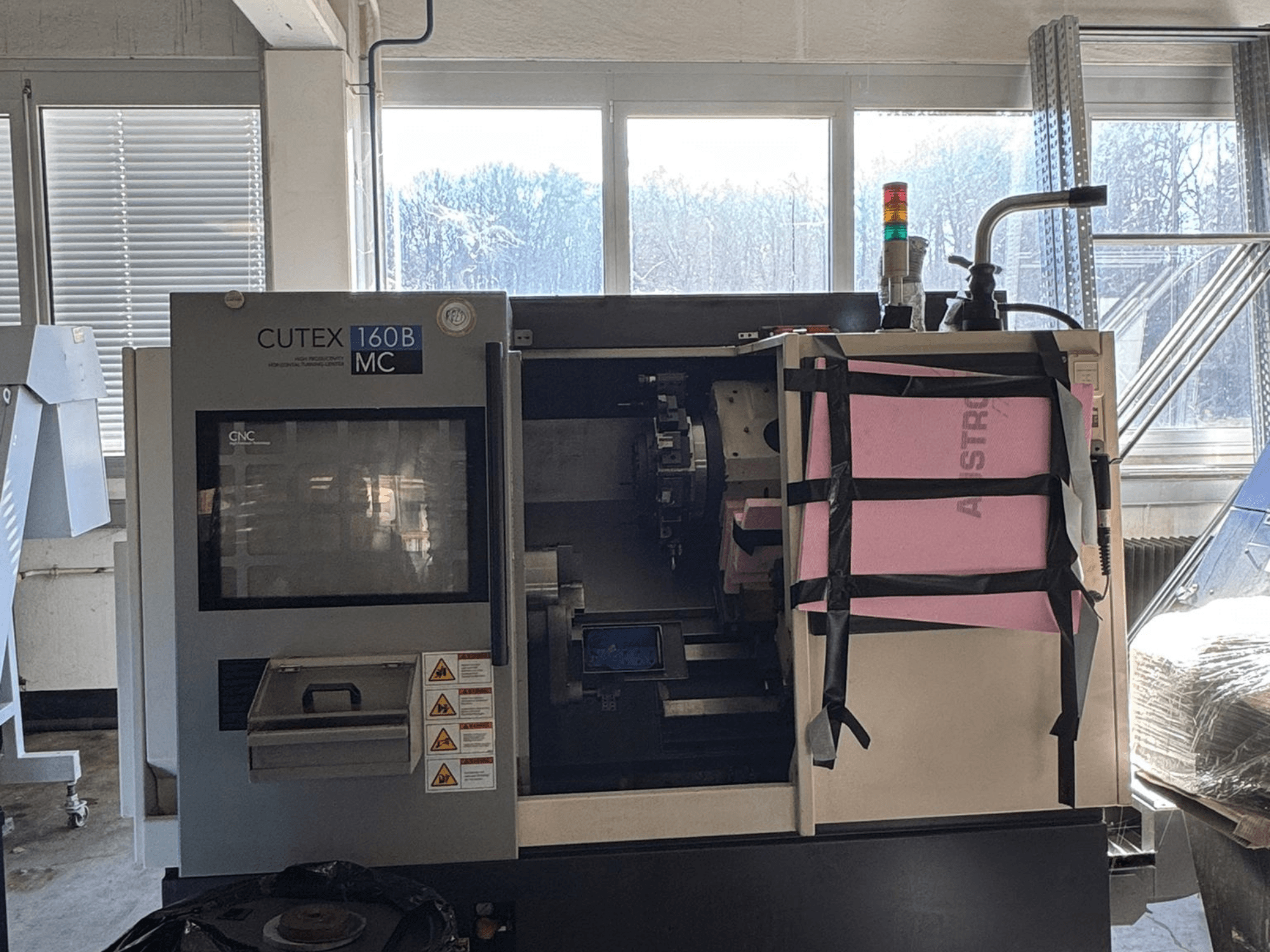 Vooraanzicht van de HWACHEON CUTEX 160 B VDI horizontale draaibank met bedieningspaneel en koelvloeistoftank, voorzien van een veiligheidslampje.