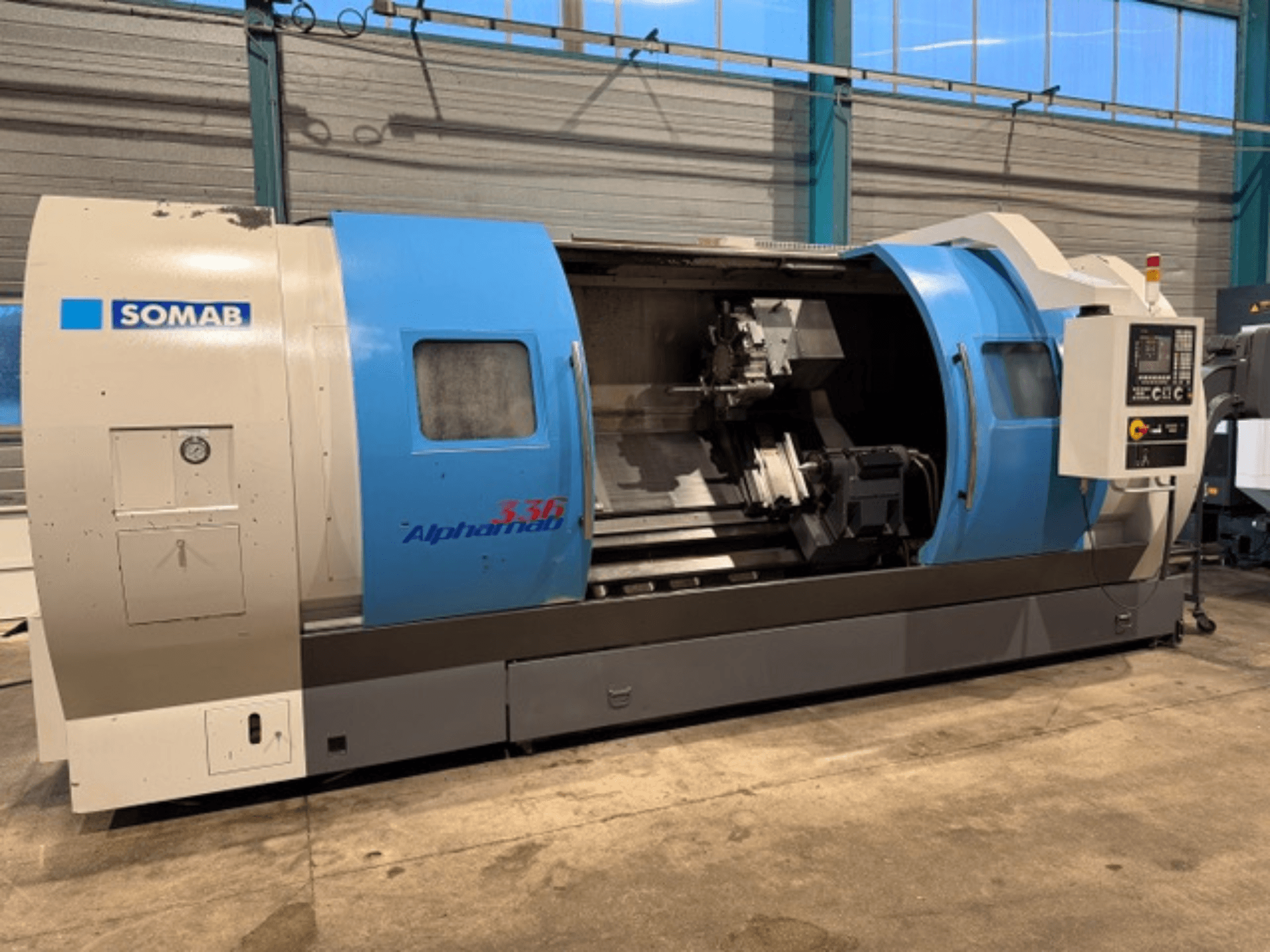 SOMAB Alpha 336 CNC draaibank, vooraanzicht, met blauwe en grijze behuizing en een bedieningspaneel aan de zijkant voor de bediening.