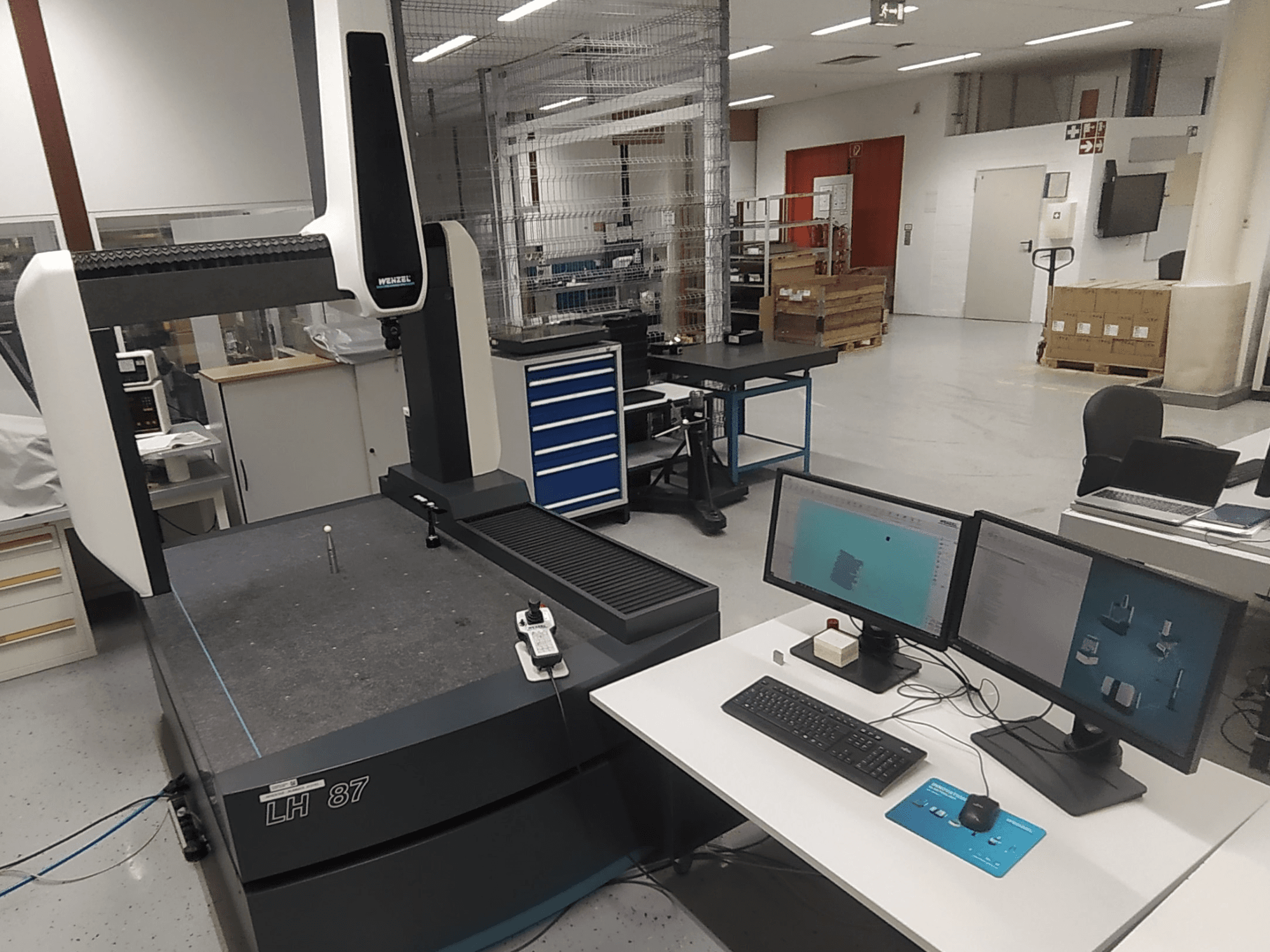 Wenzel LH 87 coördinaten meetmachine zichtbaar in een lab, met twee monitoren en een meettaster op de tafel.