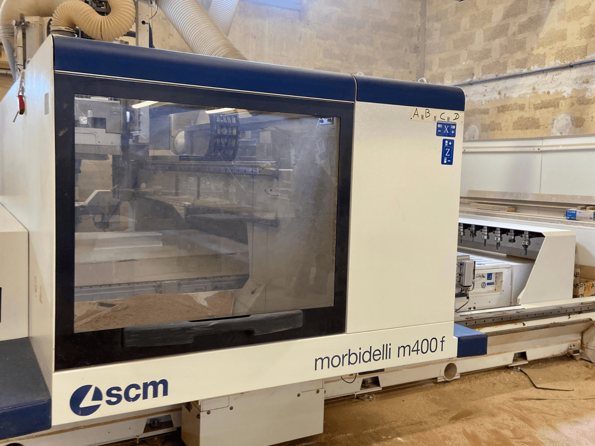 SCM Morbidelli M400F CNC machine, vooraanzicht, met een bedieningspaneel en zichtbaar zaagsel op de vloer.