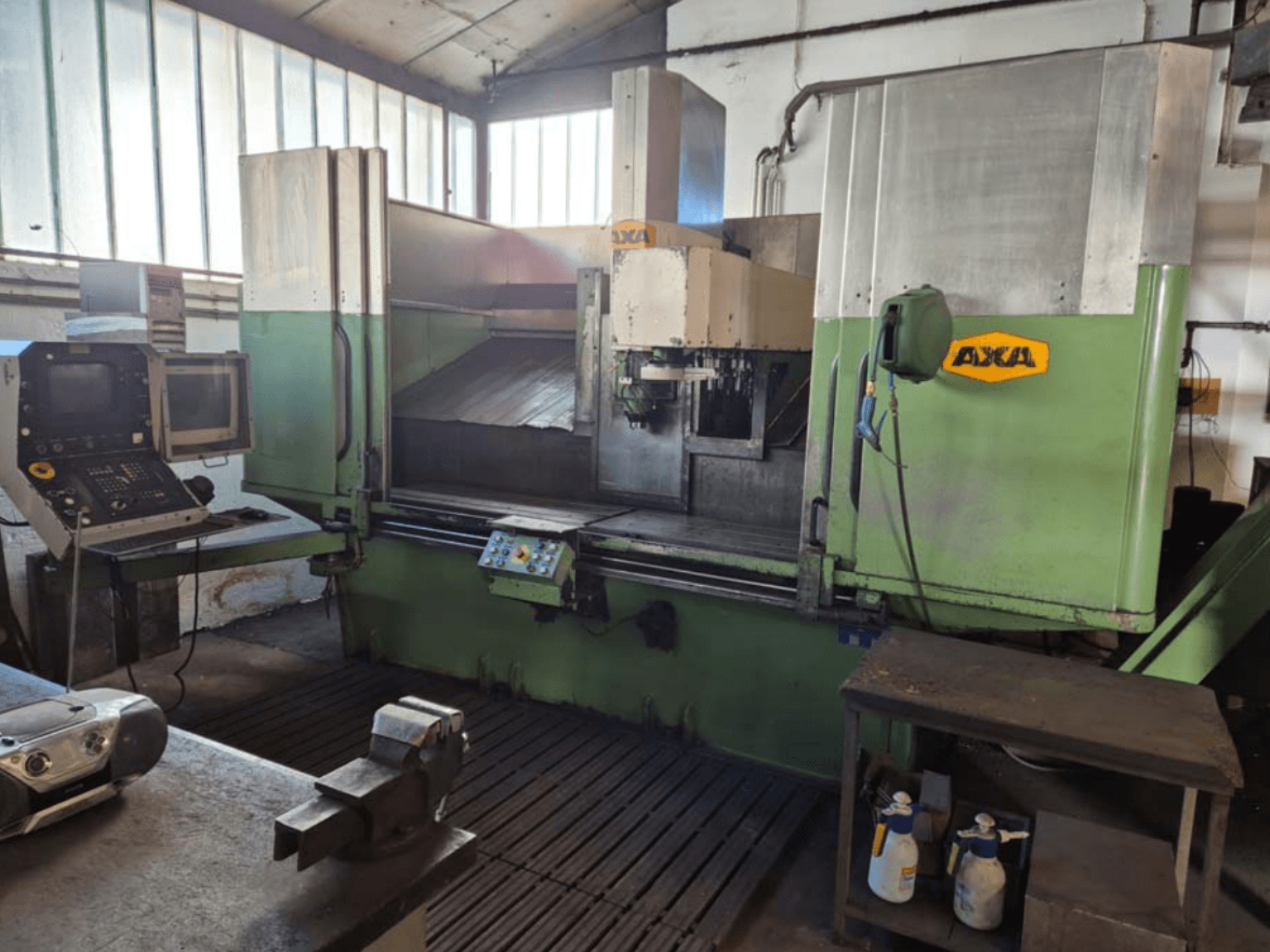 AXA VSC-2M verticaal bewerkingscentrum, vooraanzicht, voorzien van bedieningspaneel en werkruimte met snijgereedschap en schoonmaakspullen.