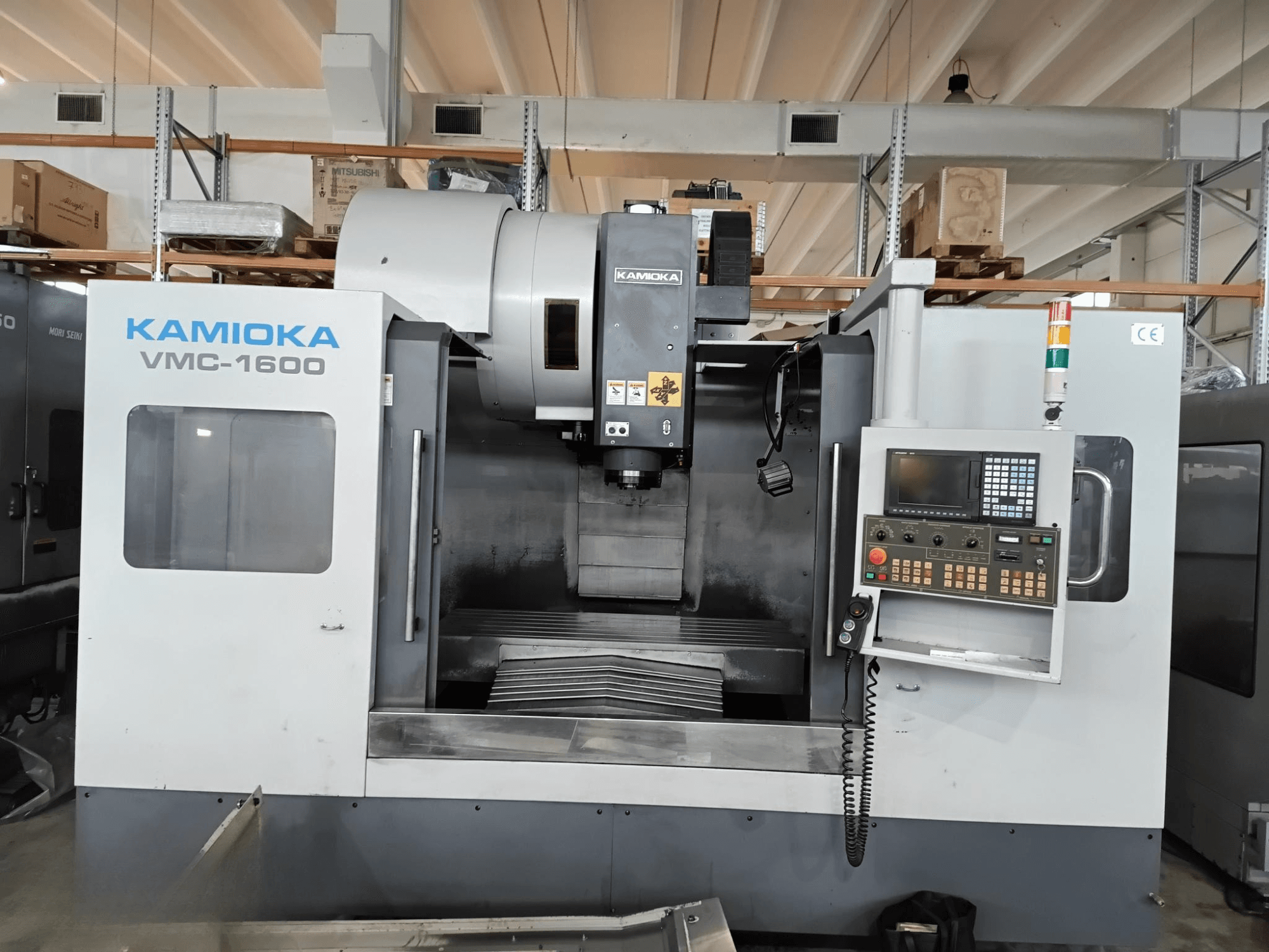 Kamioka VMC-1600 verticaal bewerkingscentrum in een fabrieksopstelling, vooraanzicht met bedieningspaneel en zichtbaar bewerkingsbed.