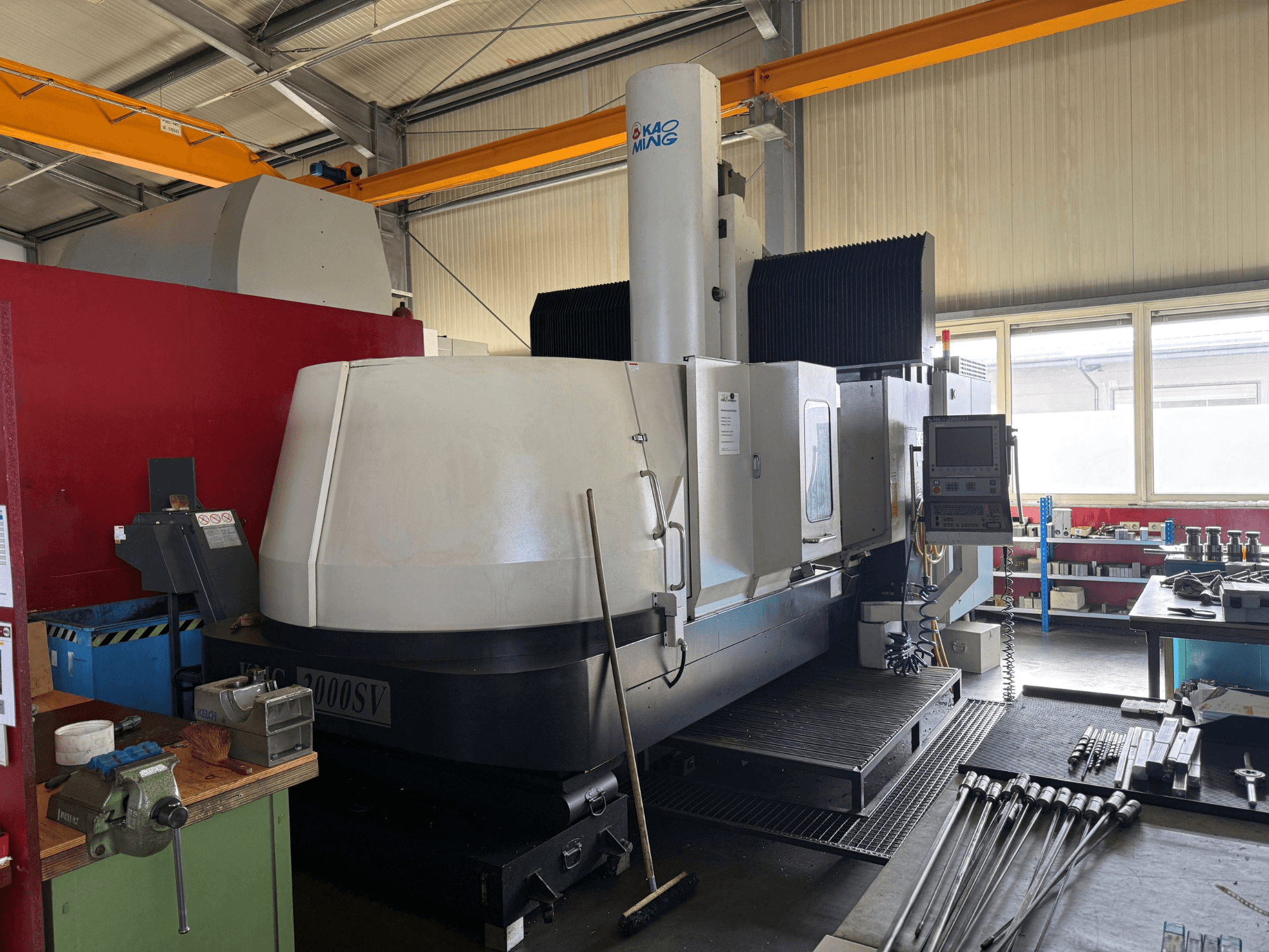 KAOMING KMC-2000 SV-portalfreesmachine in een werkplaats, vooraanzicht met zichtbaar bedieningspaneel en omliggende gereedschappen.