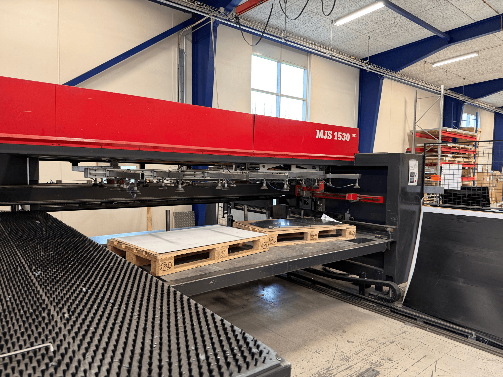 MJS 1530 CNC machine in een werkplaats, vooraanzicht, met een houten pallet die een metalen plaat vasthoudt op een verhoogd platform.