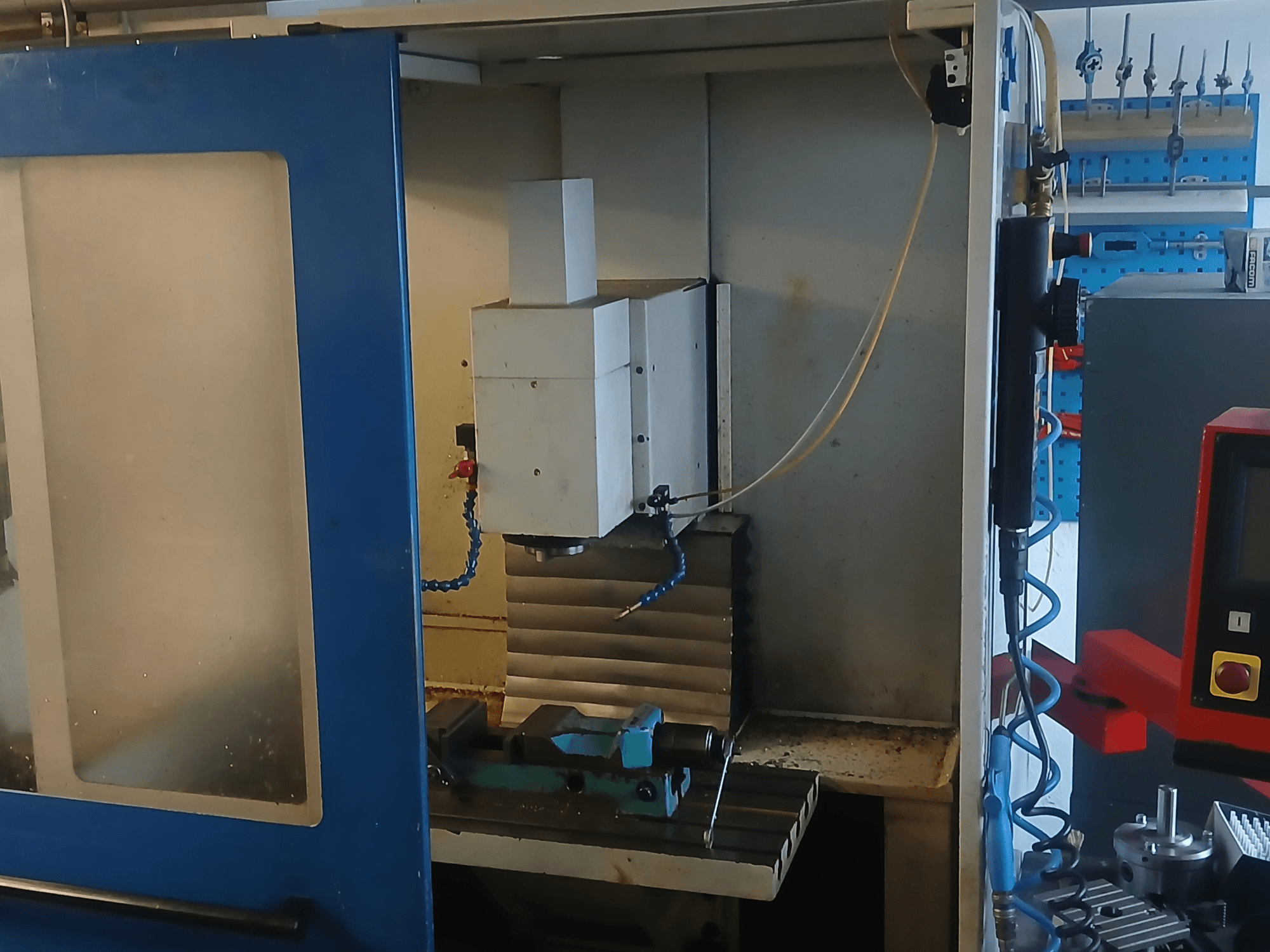 Verticaal bewerkingscentrum MACMON M 454 V, gezien vanaf de voorkant, met de spil en het bewerkingsgebied in beeld, met gereedschappen ernaast.