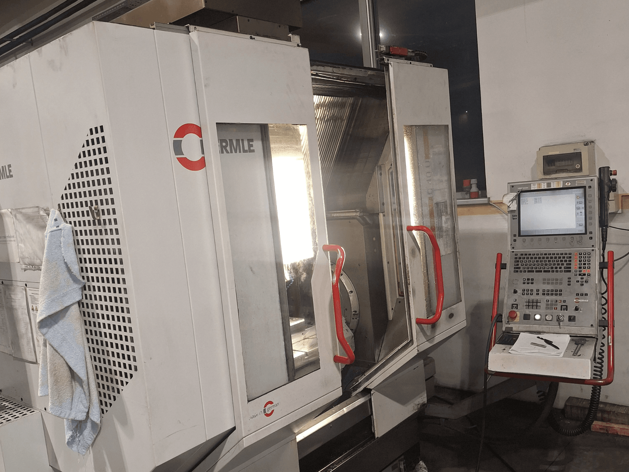 CNC machine van het merk Cormile, vooraanzicht met gedeeltelijk geopende deuren en bedieningspaneel met scherm en knoppen.