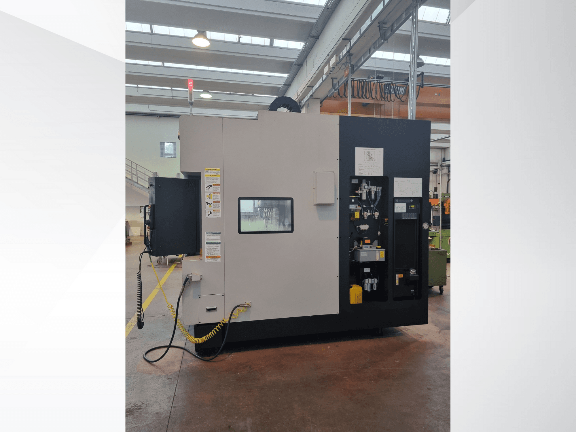 Industriële machine in zijaanzicht, met een bedieningspaneel met knoppen, indicatoren en een veiligheidswaarschuwingslabel.