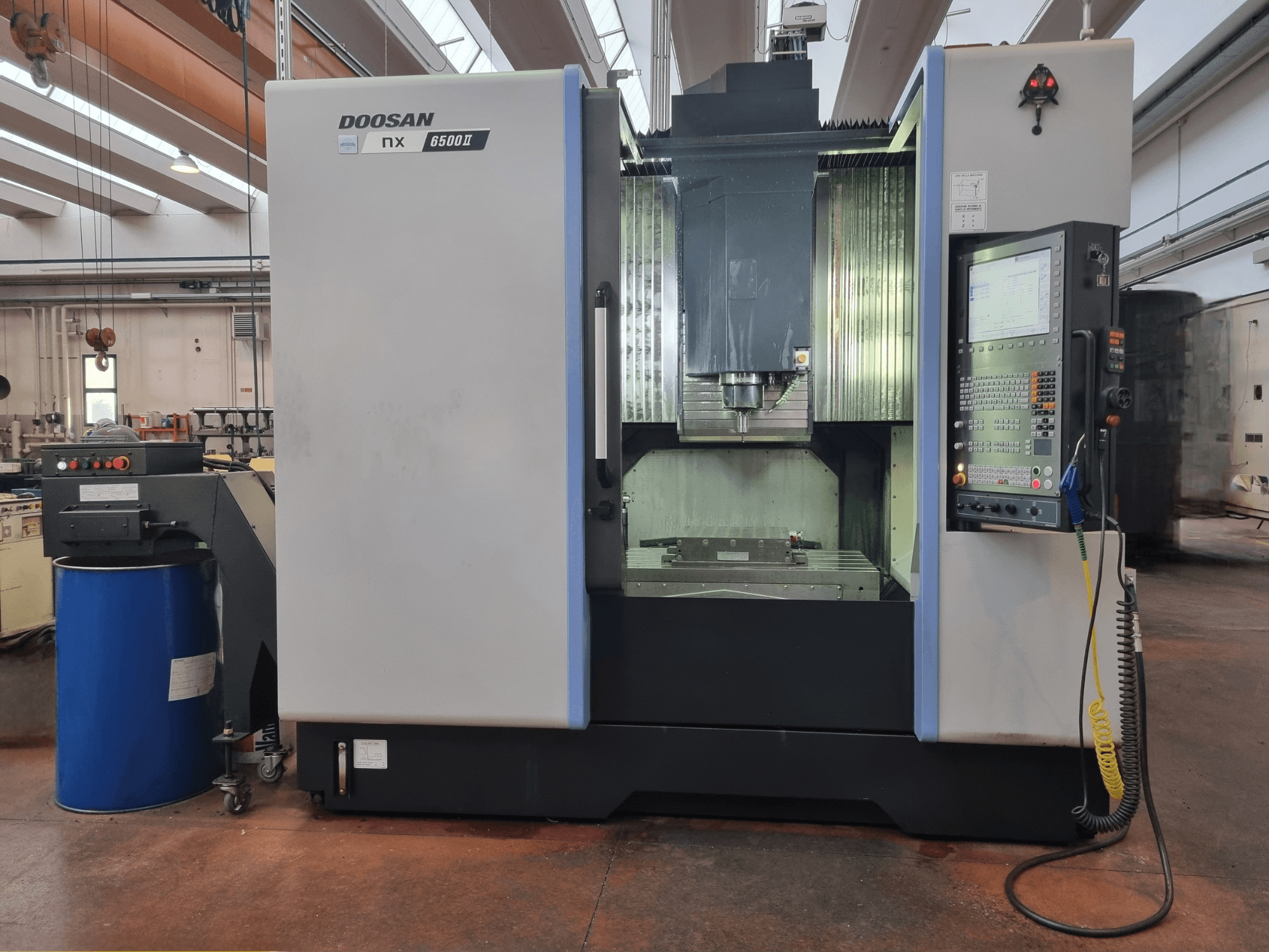 Doosan NX 6500 II CNC machine, vooraanzicht, met bedieningspaneel en bewerkingsgebied, geplaatst naast een blauwe loop.