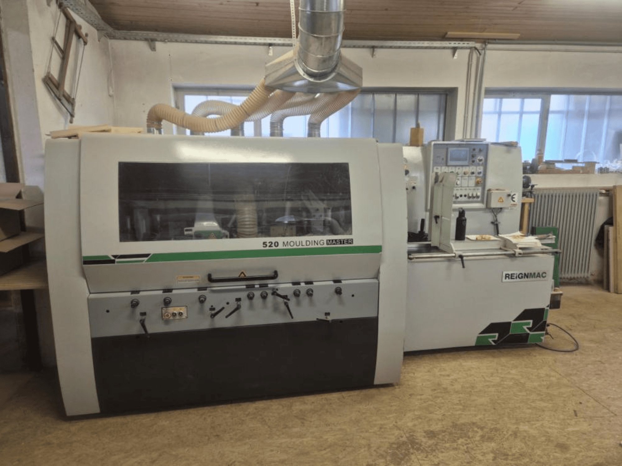 Vooraanzicht van de REIGNMAC 520 MOULDING MASTER houtschaaf, met het bedieningspaneel, de invoerrollen en het stofafzuigsysteem.