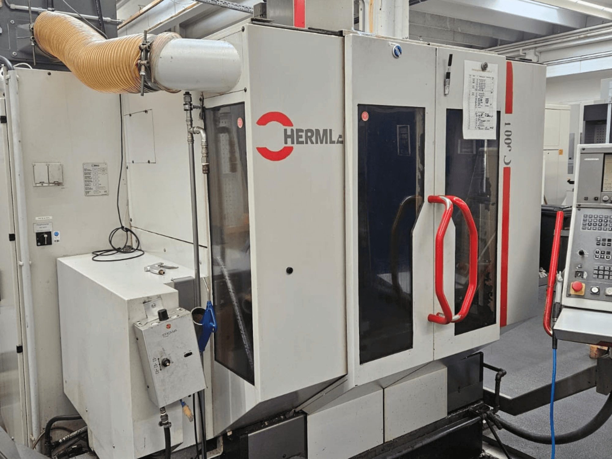 Vooraanzicht van het universeel bewerkingscentrum HERMLE C 600 U, met het bedieningspaneel en de rode hendels op de deuren.