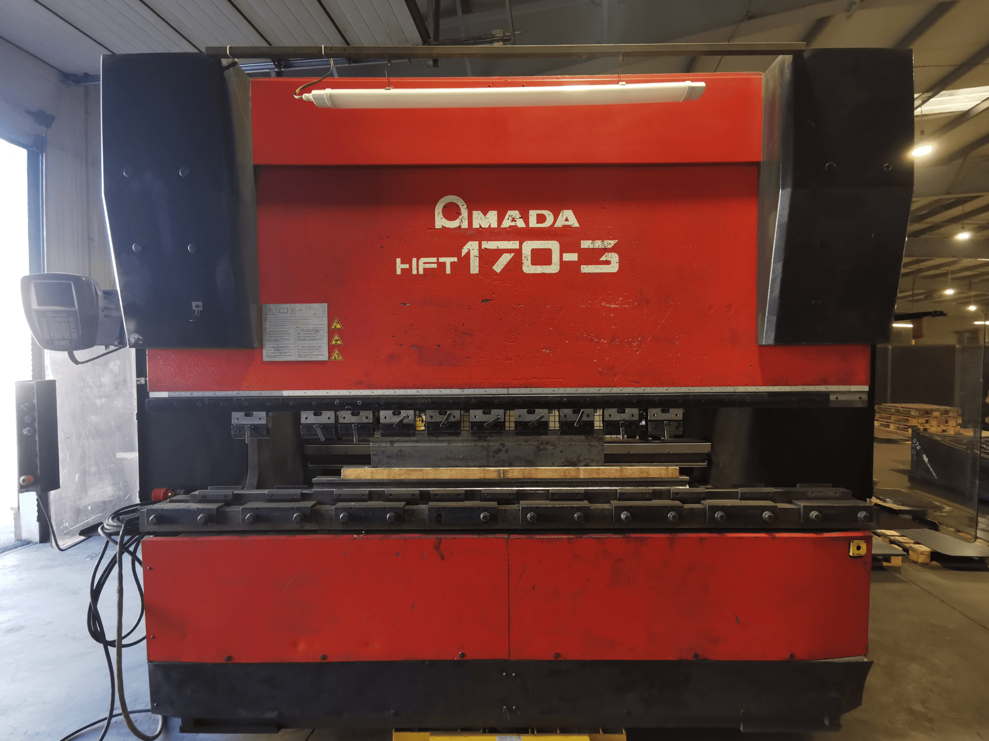 Rode Amada HFT 170-3 afkantpers gezien vanaf de voorkant, met het bedieningspaneel, de buiggereedschappen en het werkoppervlak.