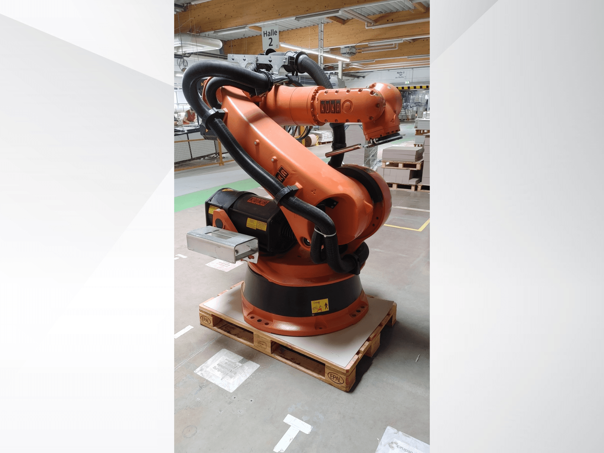KUKA KR140-3 COMP robotarm in oranje, vooraanzicht op een houten pallet, met een gebogen arm en bedieningskast.