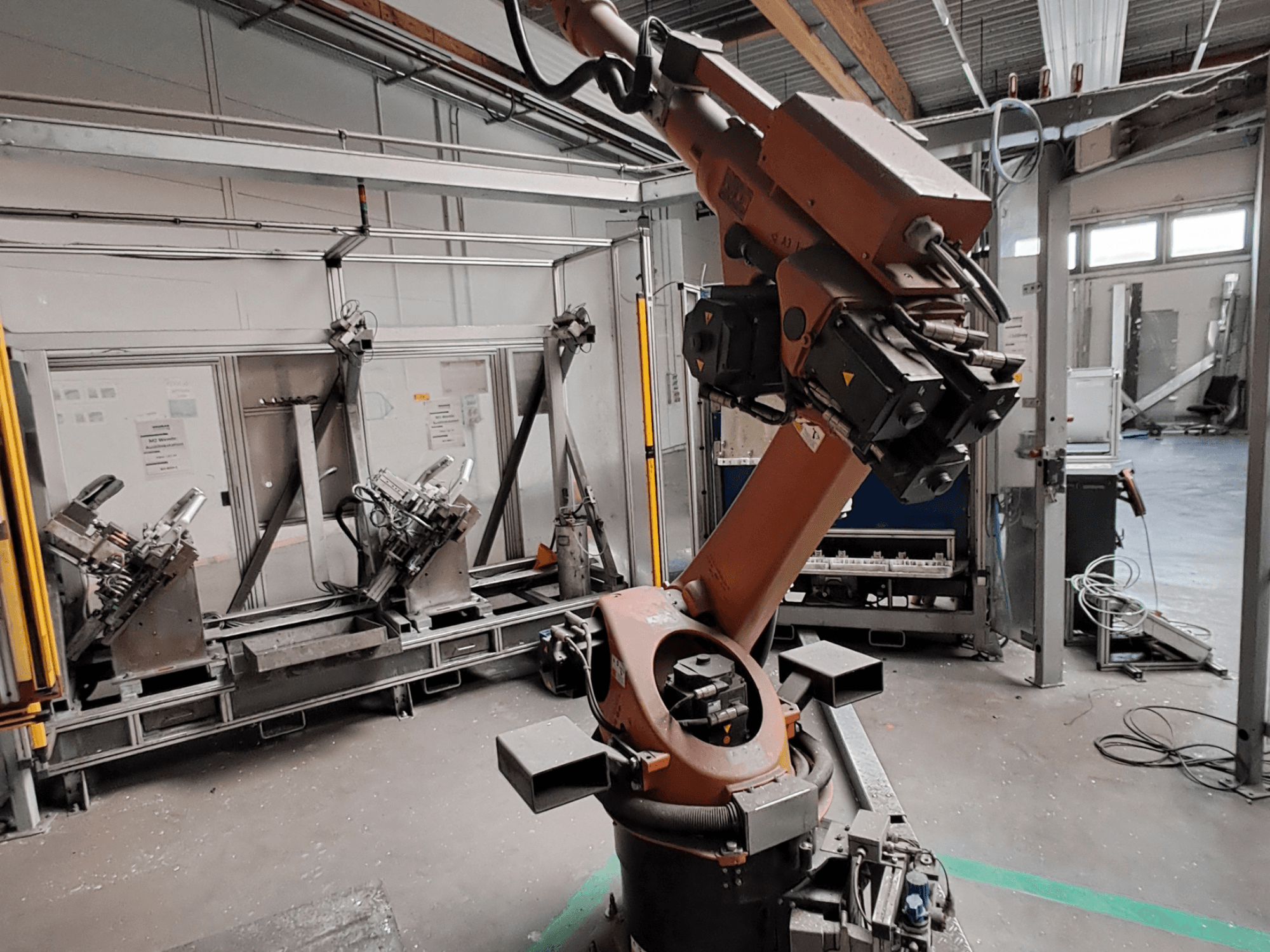 KUKA KR 30L16-2-robotarm in een industriële omgeving, zijaanzicht, waarbij de gewrichten en grijpgereedschappen van de arm te zien zijn.