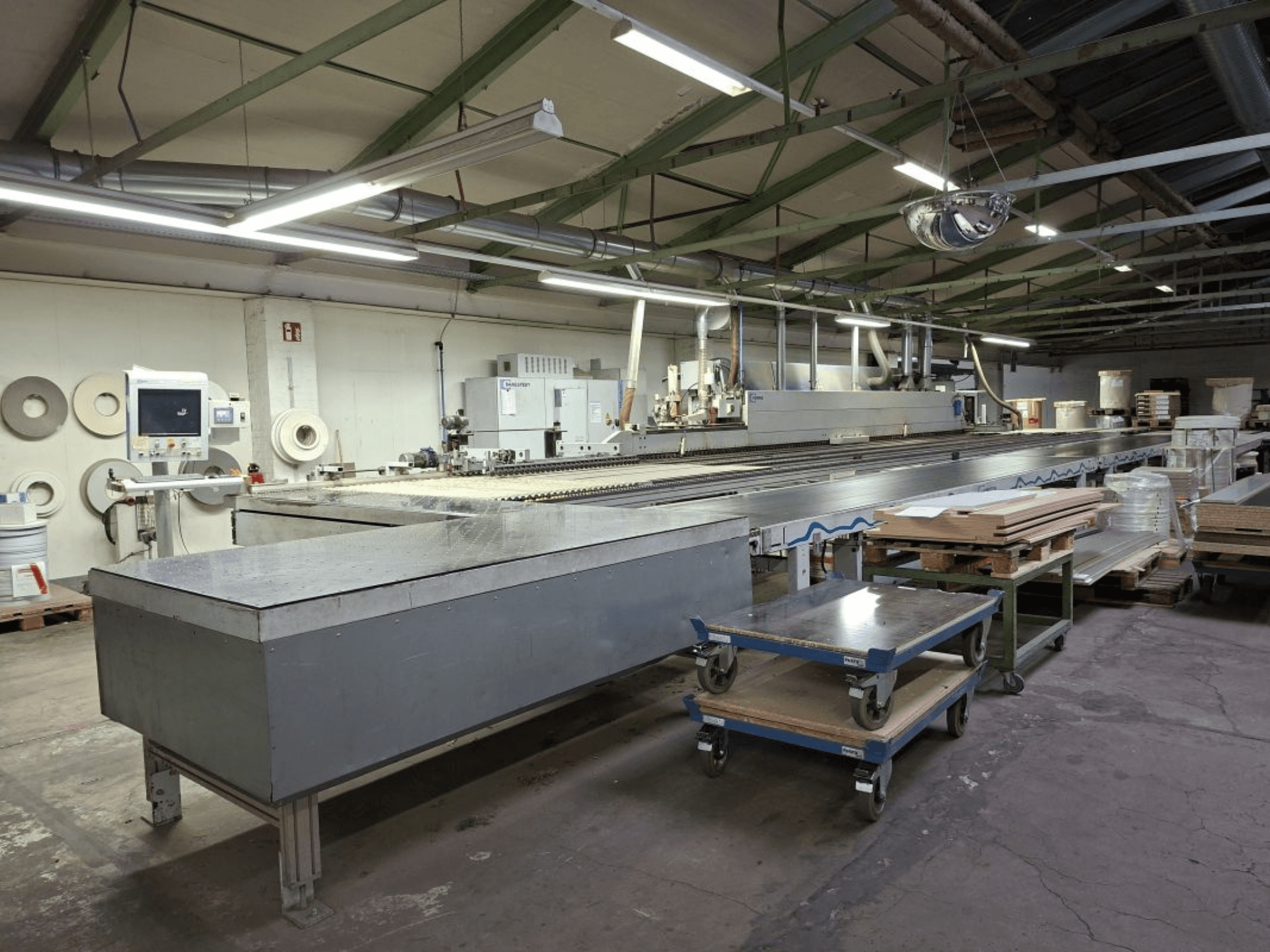 HOMAG Optimat KAL 330 kantenbewerkingsmachine gezien vanaf de zijkant, met een lange transporttafel en bedieningspaneel in een werkplaats.