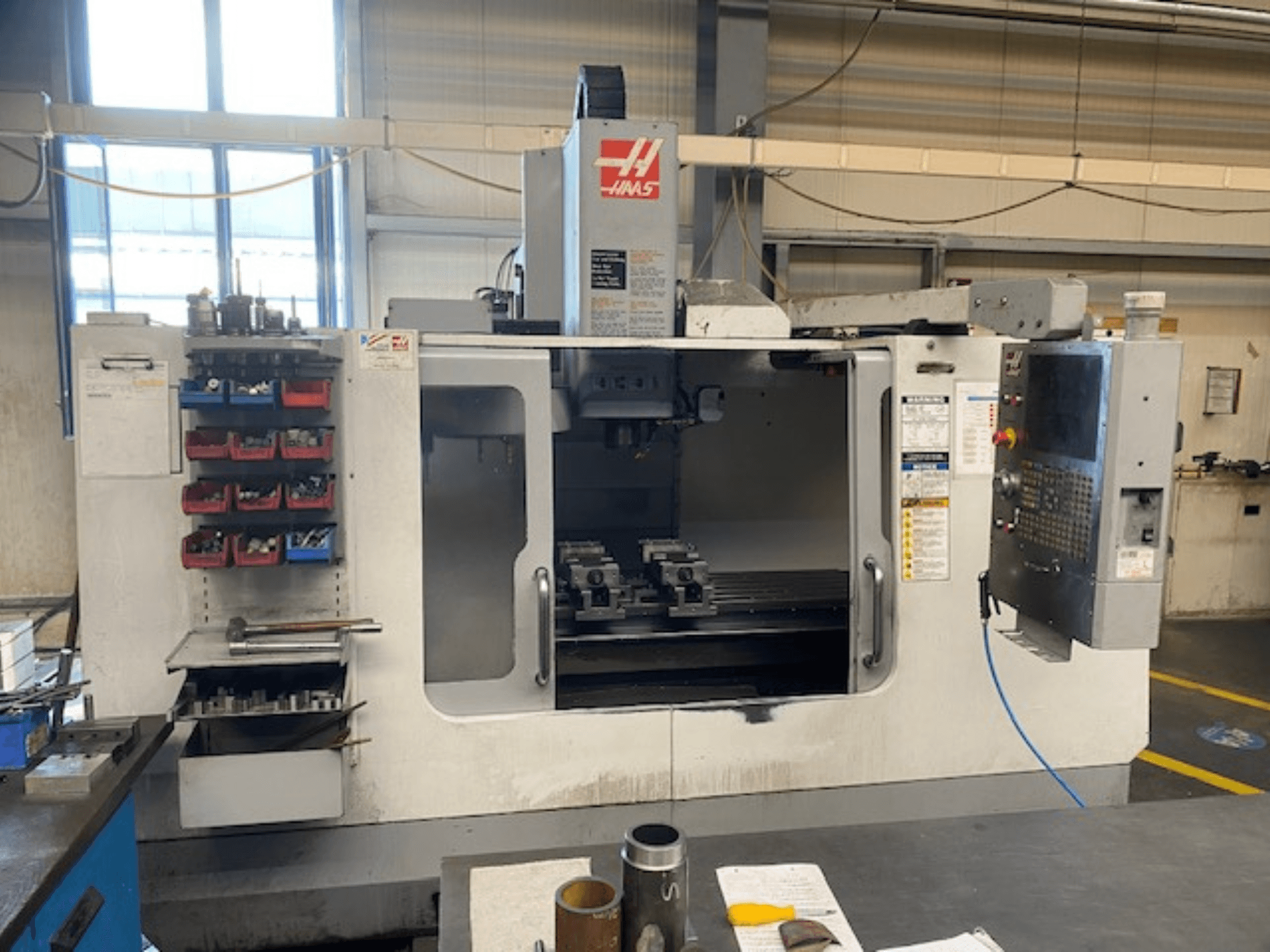 Vooraanzicht Haas CNC freesmachine, model VF-2, met gereedschapopslag, bedieningspaneel en werkruimte gereedschappen zichtbaar.
