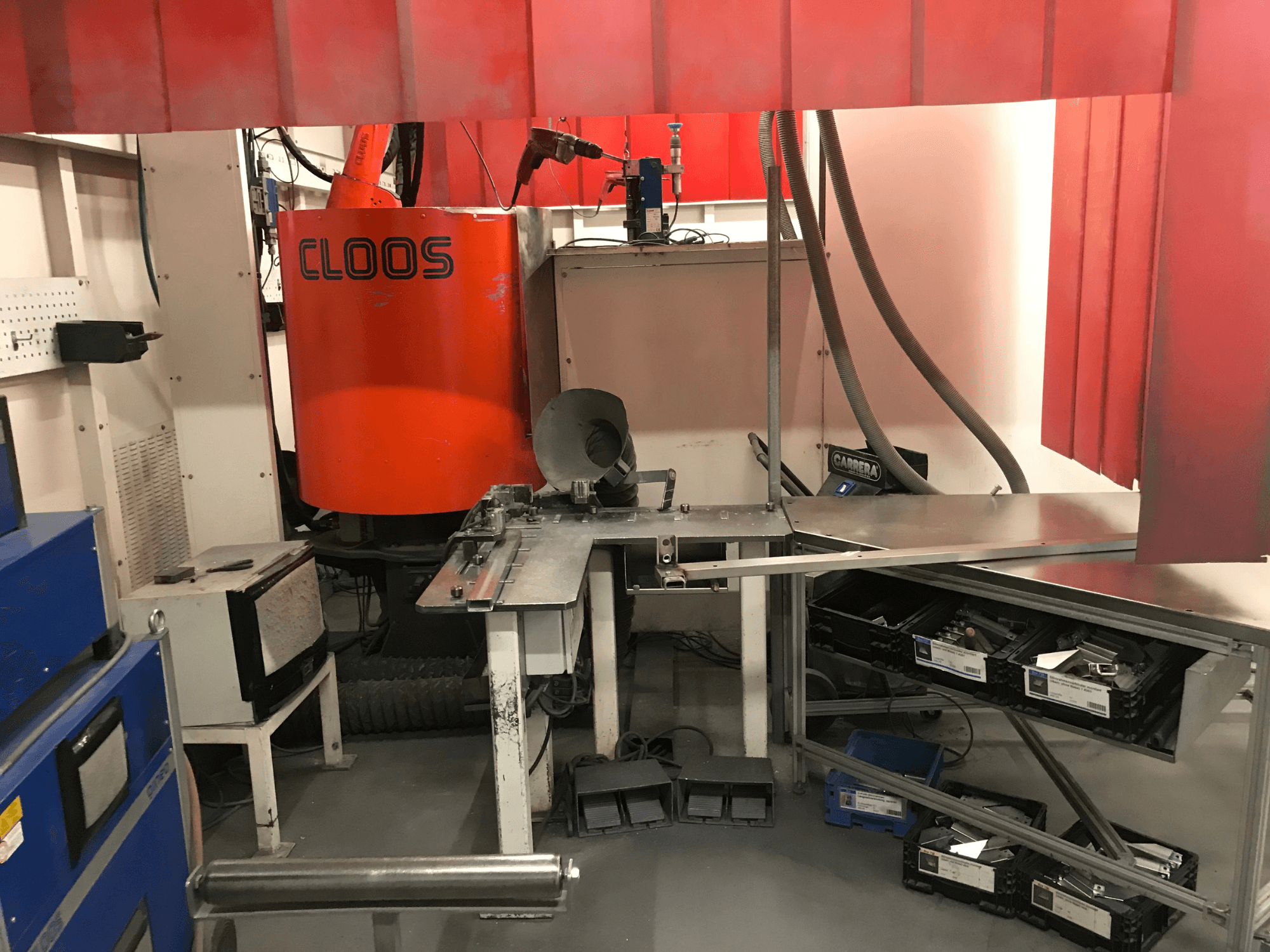 Laswerkplaatssysteem van DESSAUER, vooraanzicht met robotarm, werktafel voor metaalbewerking en opslagruimtes in een werkplaatsomgeving.