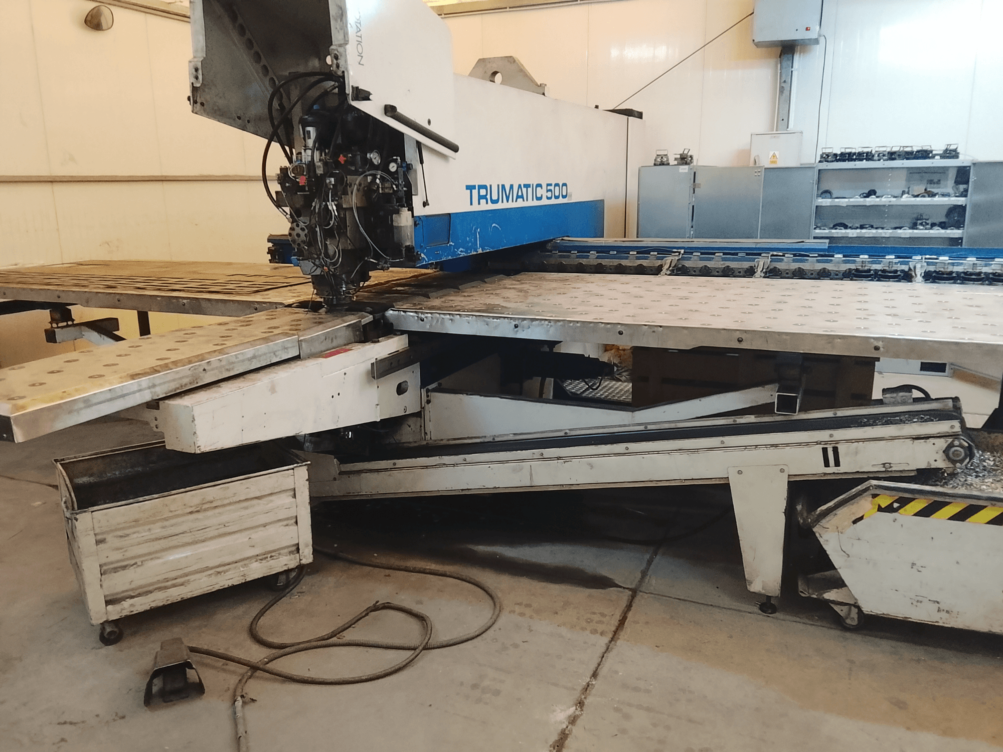 TRUMATIC 500 CNC machine in een werkplaats, zijaanzicht met snijkop en metalen werktafel met voorgeboorde gaten.